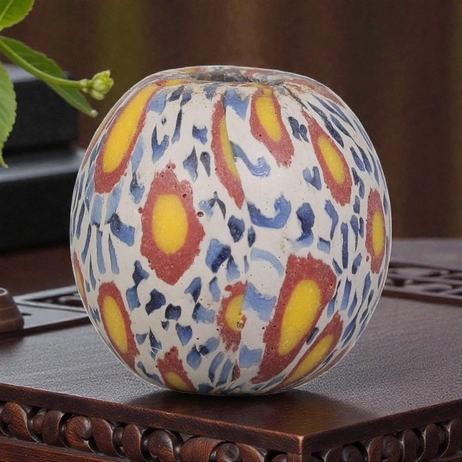Antique Glass Bead - Islamic Jatim Polychrome Eye Mosaic, 49YH: A spherical glass bead of Islamic Jatim type, crafted from polychrome mosaic glass. The surface features repeating eye motifs with bright yellow centers and red borders, set against a white ground int