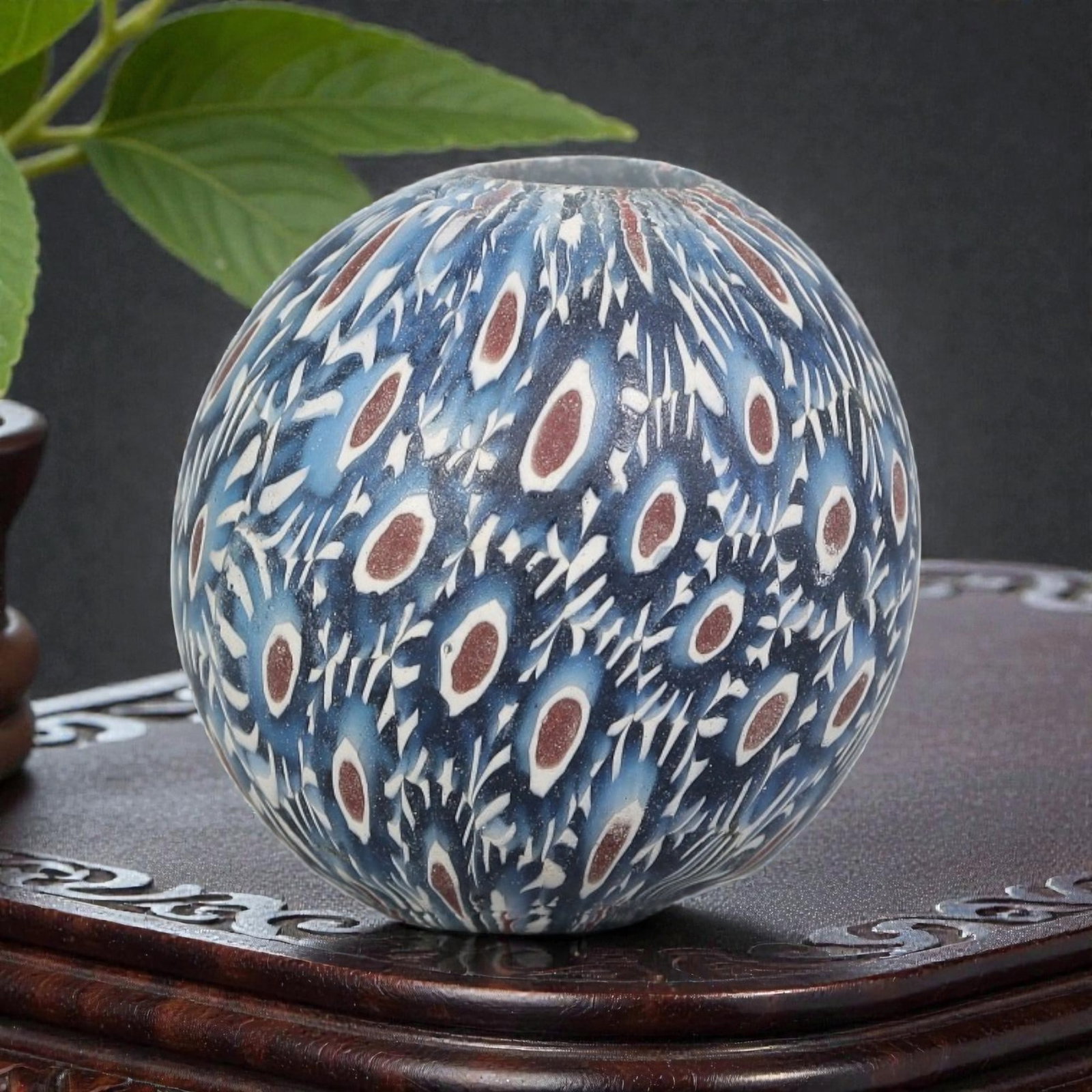 Antique Glass Bead - Islamic Jatim Indigo Peacock Feather Mosaic, 54YH: A spherical glass bead of Islamic Jatim type, crafted from polychrome mosaic glass. The surface features a dense peacock feather motif, with repeating eye patterns (reddish-brown centers framed by whi