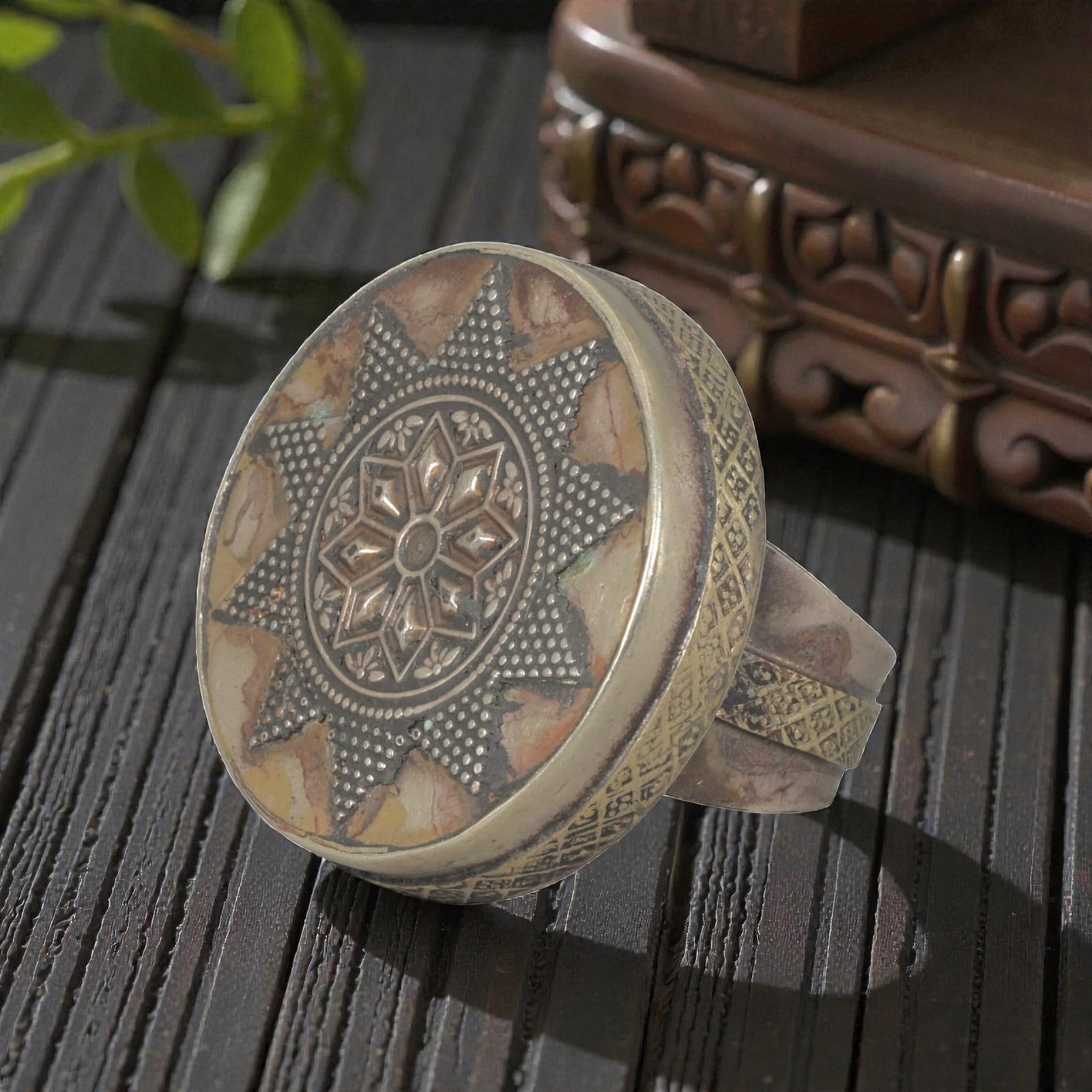 A Central Asian Silver Plated Geometric Star Motif Ring, Late 19th-Early 20th Century, 14AK: Crafted from silver plated metal with brass accents, featuring a wide, open band. The circular bezel displays a multi-layered star motif: a central eight-pointed star surrounded by small floral detail