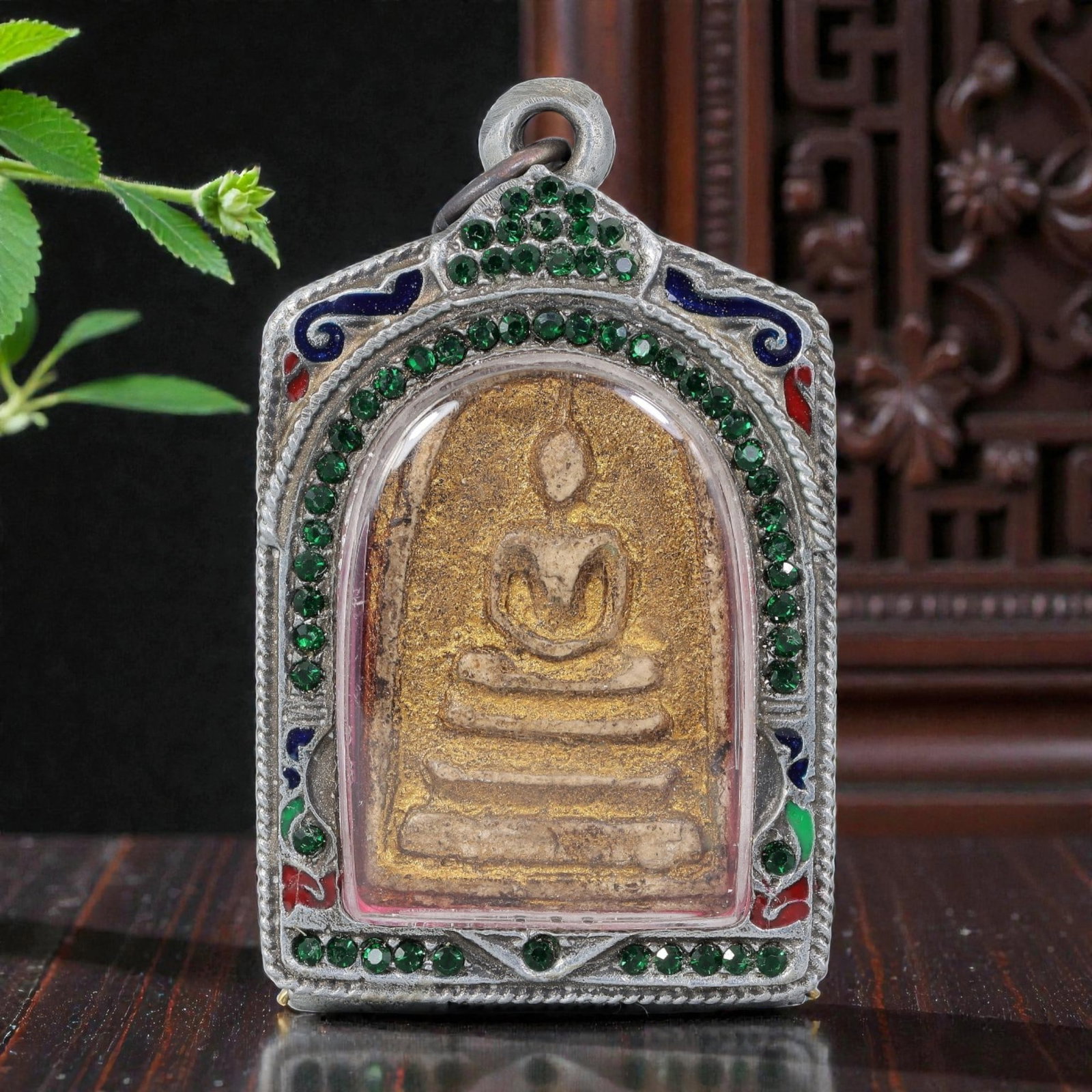 Thai Buddha Amulet - Enamel & Crystal Silver Tone Pendant, 53AP: A Thai Buddhist amulet featuring a gilded Buddha figure seated on tiered bases, housed in a silver-tone metal casing. The glass-fronted enclosure protects the aged plaque, which shows signs of patinat
