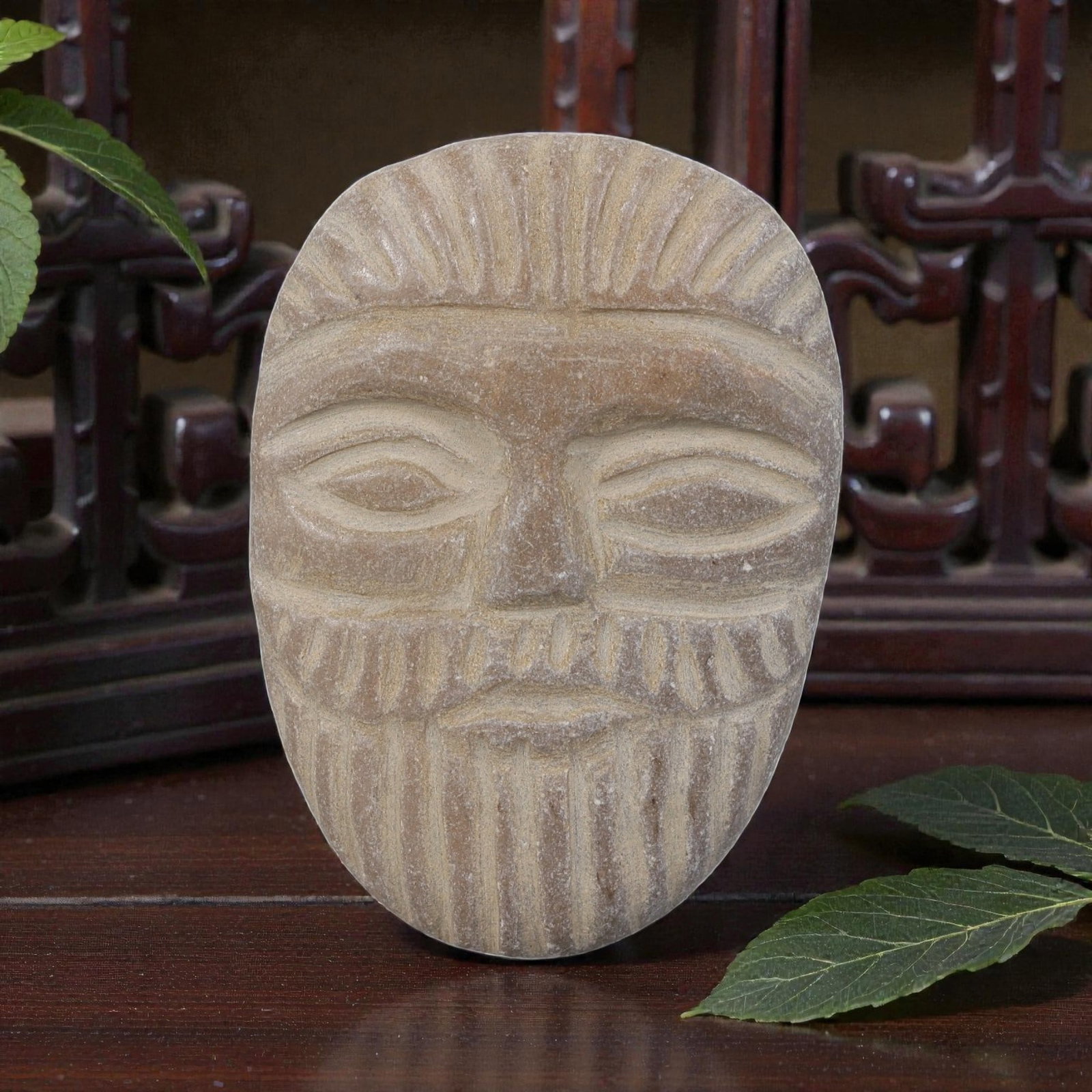 Antique Silk Road Stone Maskette, 48YD: This ancient maskette is carved from weathered light brown stone, with a smooth oval form. The face features stylized incised details depicting a full frontal human visage, including almond-shaped eye