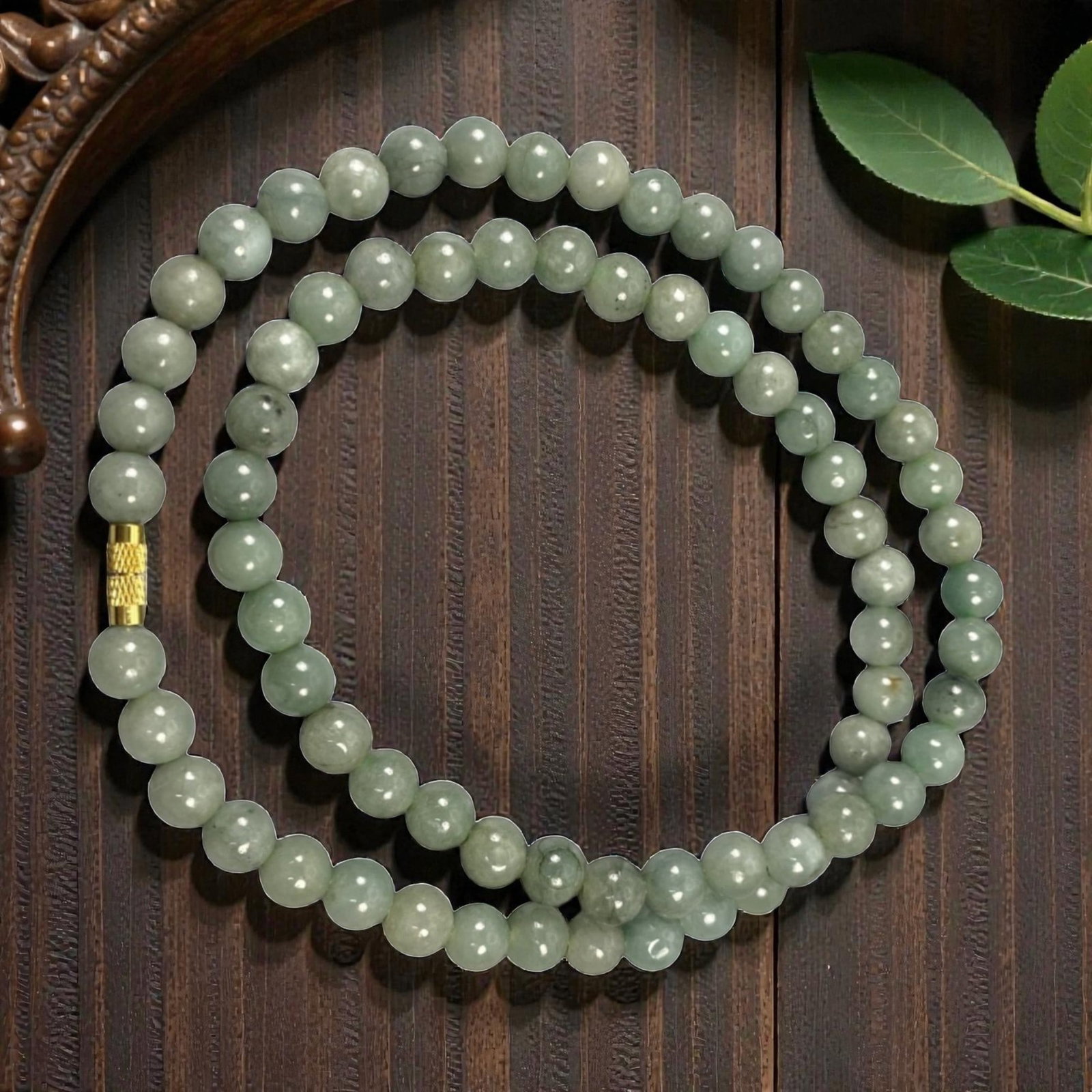 A Chinese Jadeite Jade Bead Necklace, 20th Century, 63ZK: Composed of spherical beads of uniform pale celadon green jadeite jade with subtle natural veining and minor internal inclusions, the necklace is strung in a continuous loop. The beads feature a smoot