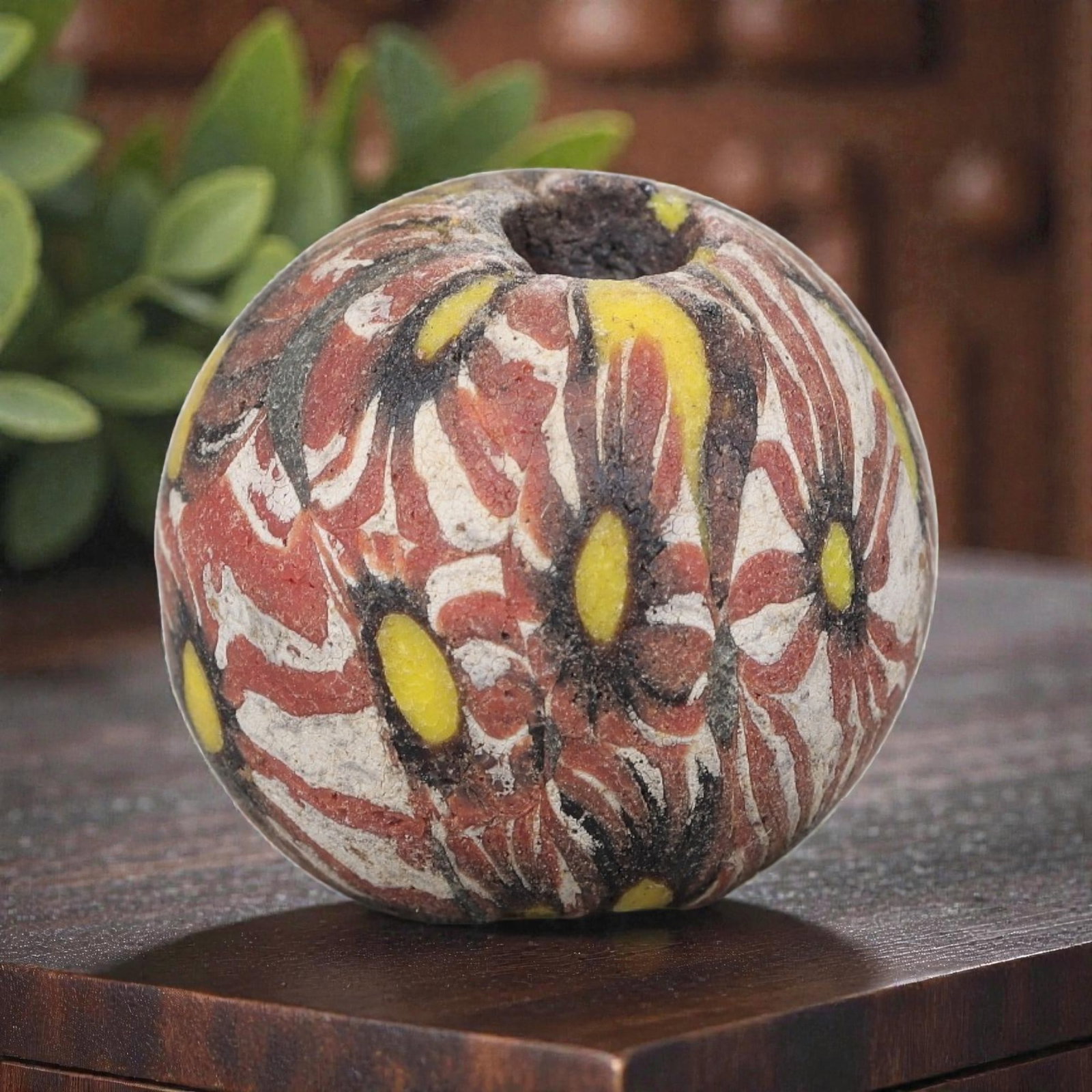 Antique Glass Bead - Islamic Jatim Red Floral Mosaic, 62AP: A spherical glass bead of Islamic Jatim type, crafted from polychrome mosaic glass. The surface features repeating stylized floral motifs with yellow centers, set against a vibrant red, white, and bla