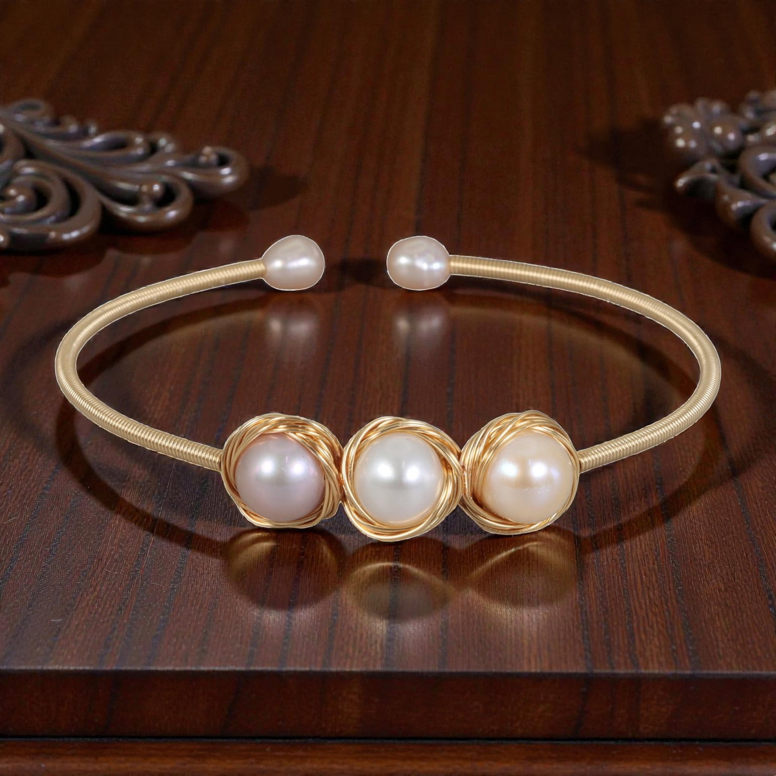 Natural Multi-Tone Freshwater Pearl Gold Wire-Wrapped Open Cuff Bracelet, 10EB: A delicate open cuff bracelet handcrafted with gold-toned wire, featuring three natural freshwater pearls in soft pink, white, and peach hues. Each pearl is individually encased in intricate wire-wrap