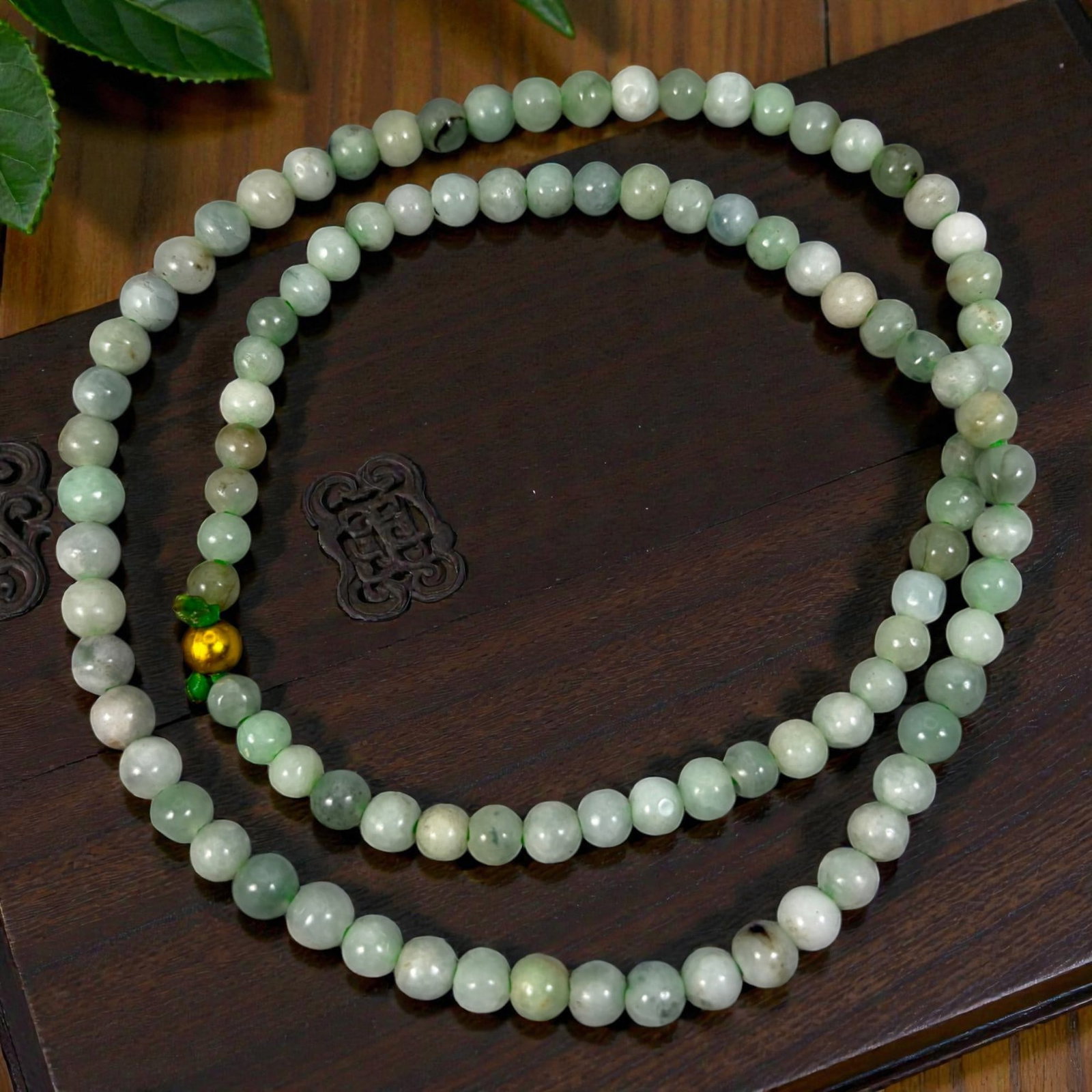 Chinese Jadeite Jade Bead Necklace, 20th Century, 94XE: A continuous strand of polished jadeite beads, each of uniform spherical form, displaying soft pale green, off-white, and light grey tones with natural inclusions, subtle variations in translucency, a
