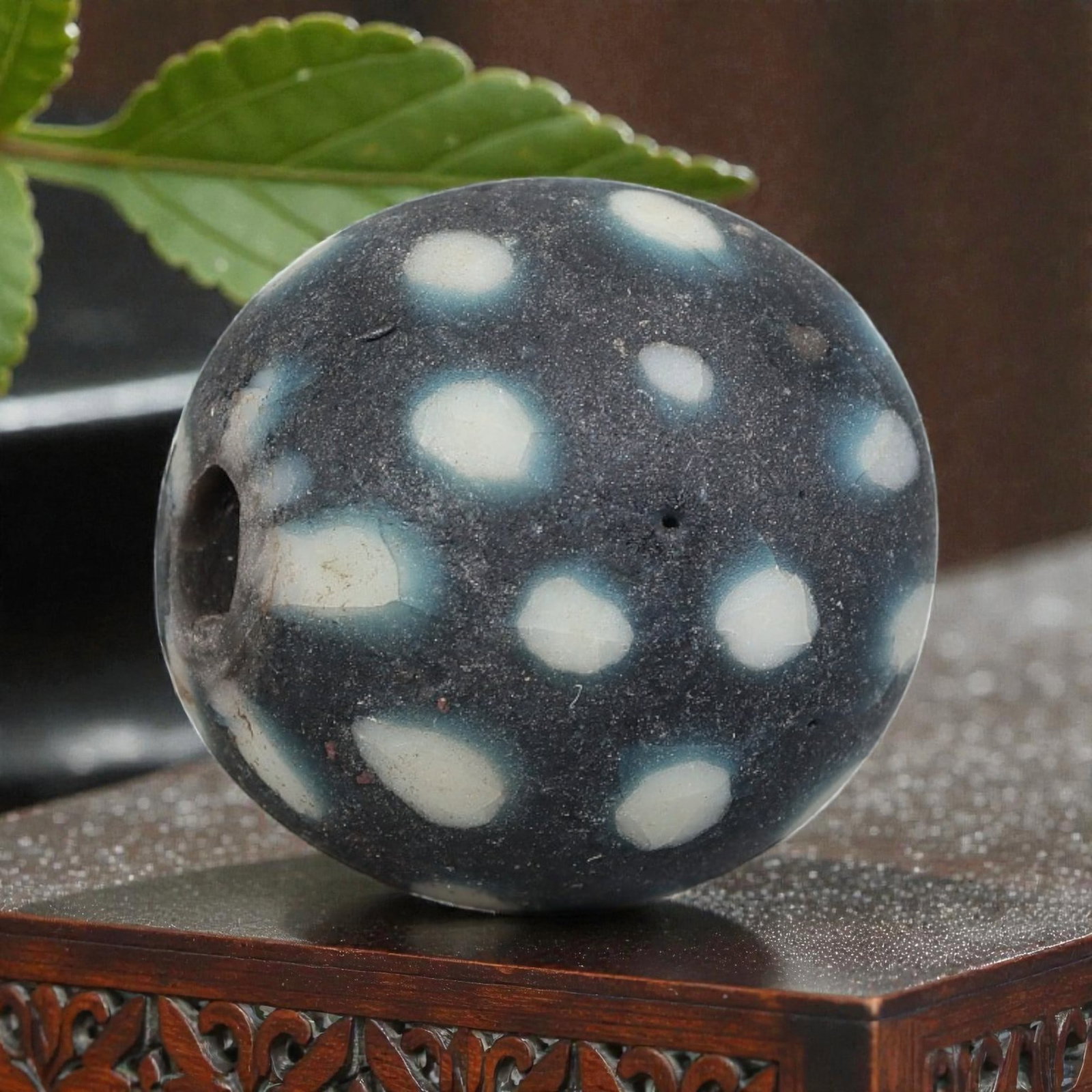 Antique Glass Bead - Islamic Jatim Black-White Polka Dot Mosaic, 65YH: A spherical glass bead of Islamic Jatim type, crafted from polychrome mosaic glass. The surface features simple yet striking white polka dots, some with subtle blue halos, set against a matte black gr