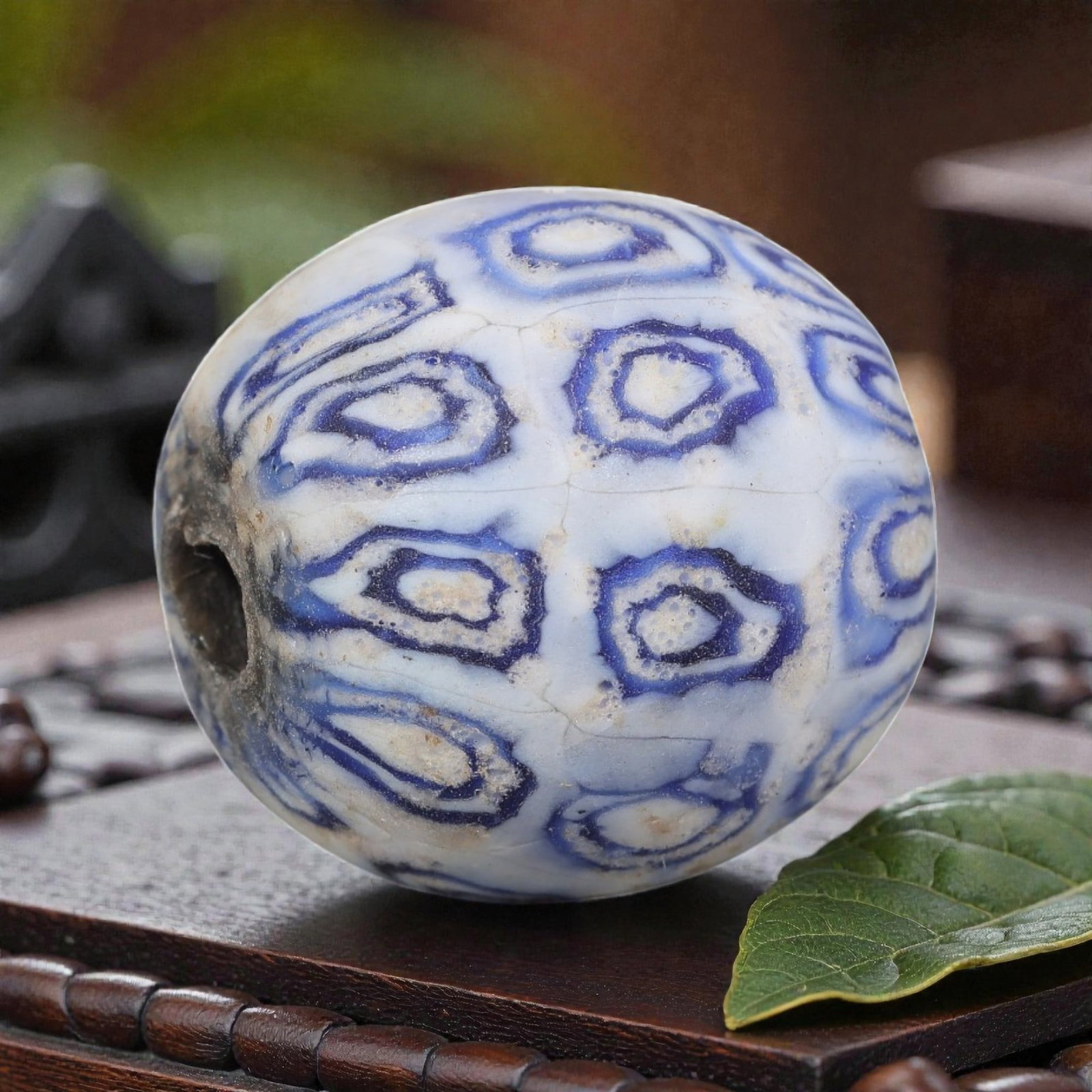 Antique Glass Bead - Islamic Jatim Blue Concentric Eye Mosaic, 60AP: A spherical glass bead of Islamic Jatim type, crafted from polychrome mosaic glass. The surface features repeating blue concentric eye motifs, with layered blue rings set against an opaque white groun