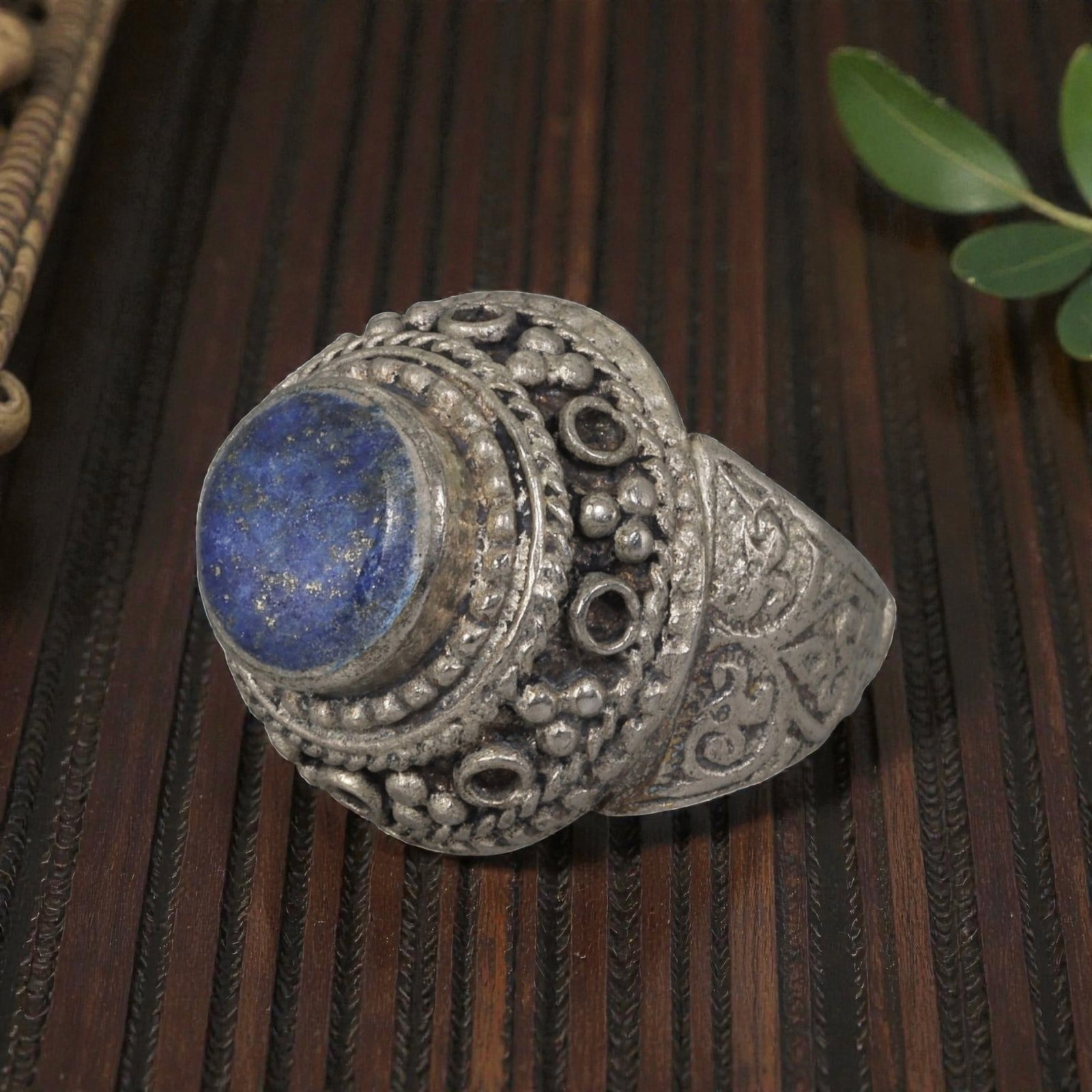 A Middle Eastern Silver Plated Lapis Lazuli Ring, Late 19th-Early 20th Century, 24AK: Set with a round cabochon lapis lazuli stone exhibiting characteristic deep blue color and natural pyrite flecks, the ring features an ornate bezel decorated with beaded granulation, twisted wirework,