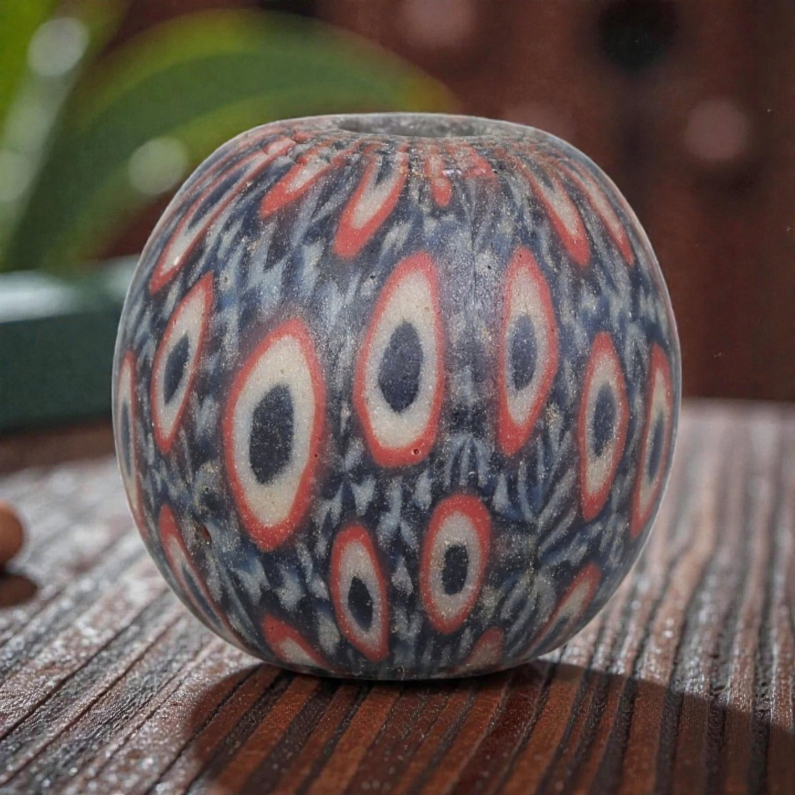 Antique Glass Bead - Islamic Jatim Red-Ring Eye Mosaic, 58YH: A spherical glass bead of Islamic Jatim type, crafted from polychrome mosaic glass. The surface features repeating concentric eye motifs with dark centers, white rings, and vibrant red outer borders, 