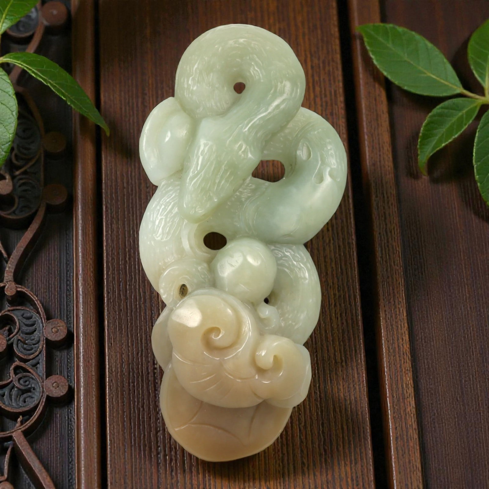A Chinese Jade Intertwined Serpents and Lingzhi Pendant, 20th Century, 36YA: Carved from pale celadon jade with areas of creamy white and warm honey-colored tonal variation, the pendant is worked as a vertically oriented composition carved in the round with openwork elements. 