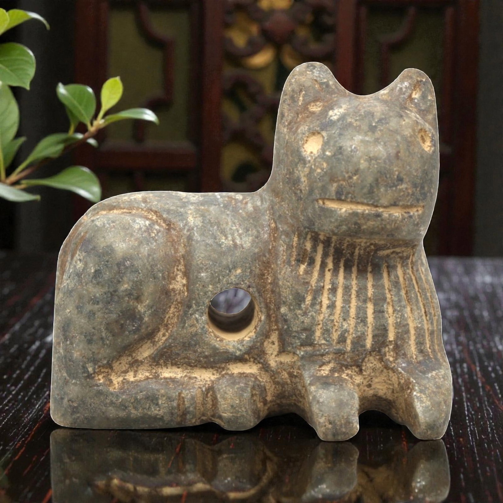Ancient Near Eastern Stone Feline Amulet, Circa 3rd-2nd Millennium BCE, 89ZP: Carved from grey stone with natural inclusions and earthy patination, the amulet depicts a recumbent feline figure. The form is stylized with simplified facial features, including incised eyes and a l