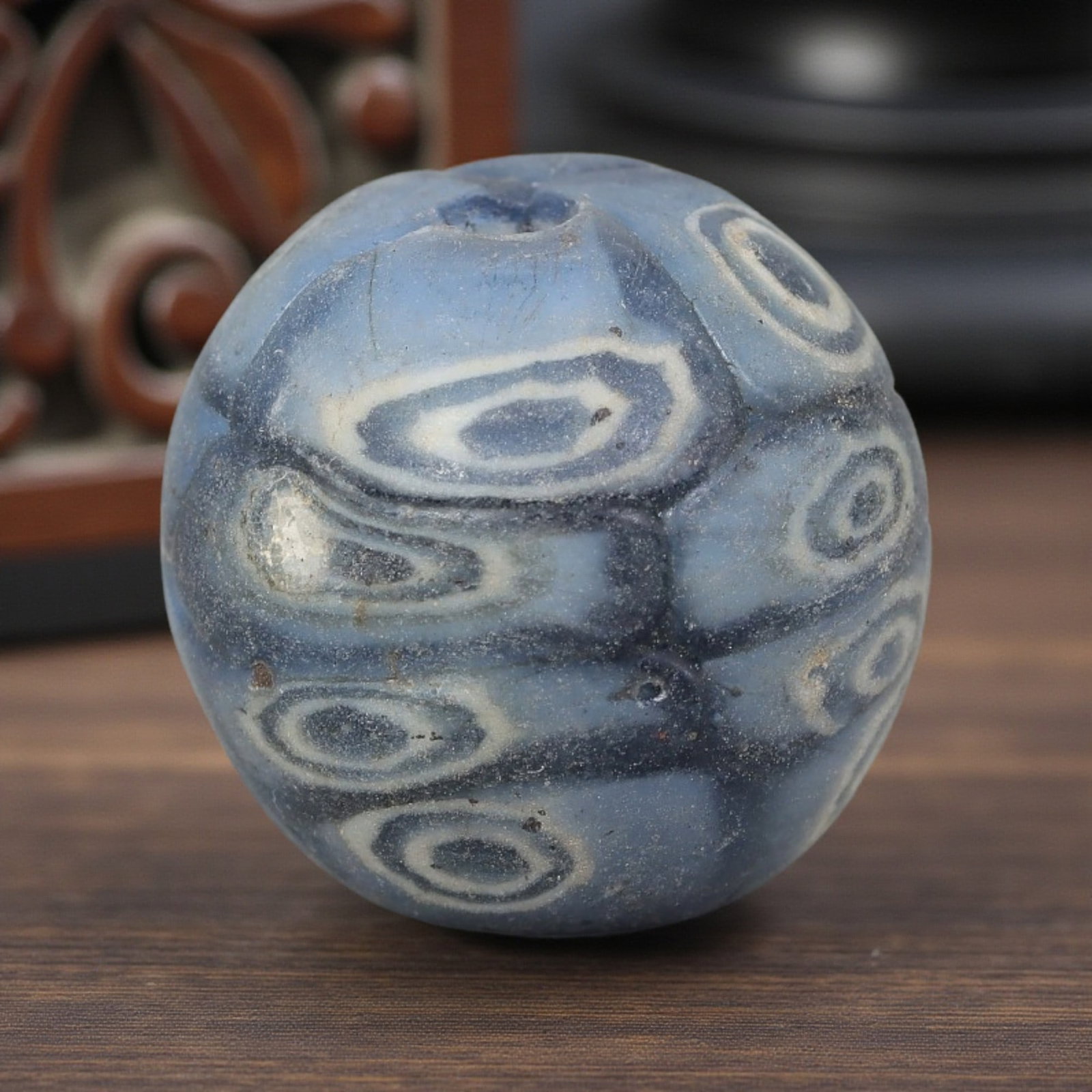 Antique Glass Bead - Islamic Jatim Pale Blue Concentric Eye Mosaic, 61AP: A spherical glass bead of Islamic Jatim type, crafted from polychrome mosaic glass. The surface features repeating concentric eye motifs in varying shades of blue and white, set against a pale blue gr