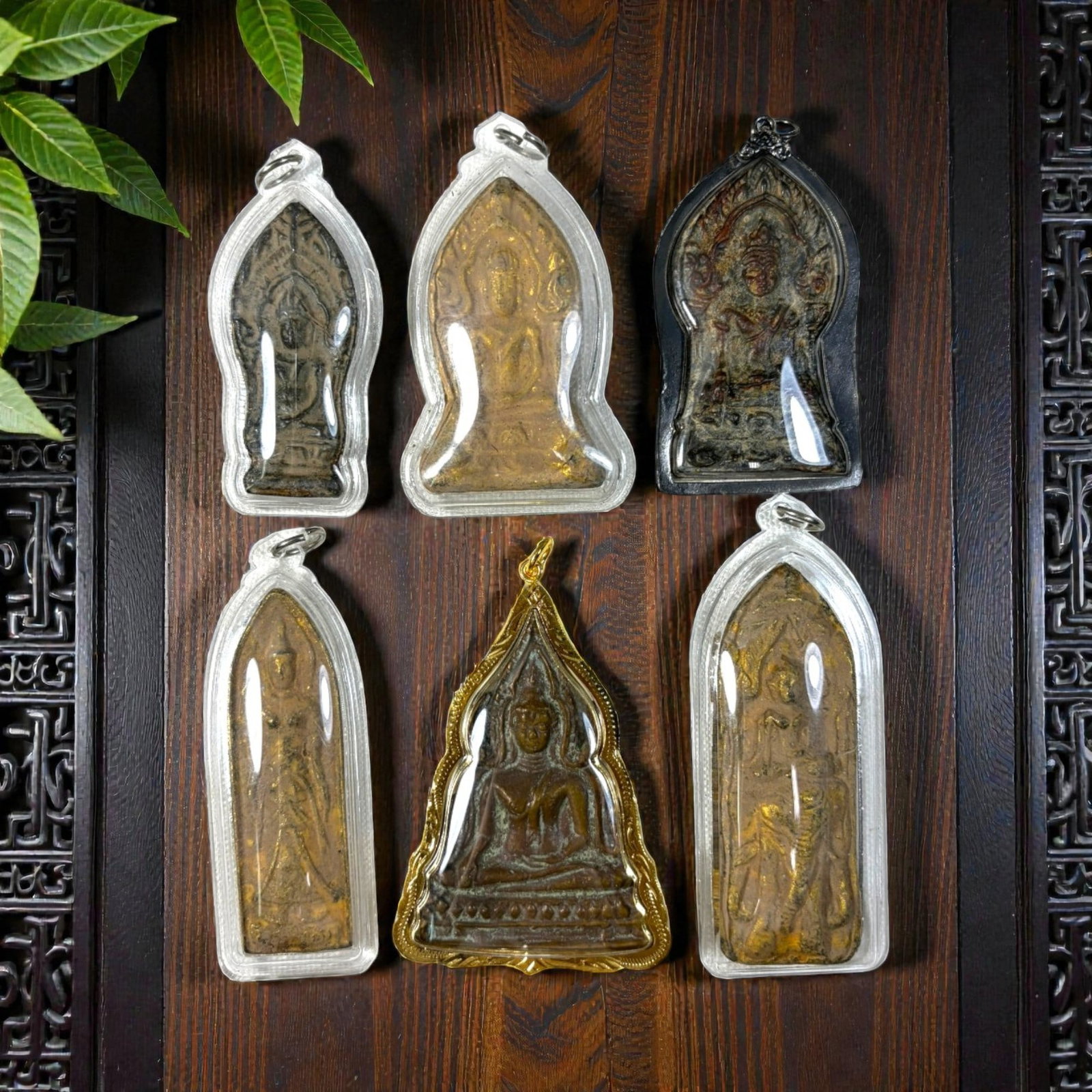 A Lot of 6 Vintage Thai Buddhist Amulets with Cases, 37AA: Comprising six pendants ranging from 7 to 9 cm in height. The group includes five amulets in clear protective plastic cases, and one seated Buddha amulet in an ornate gilt metal frame. The pieces feat