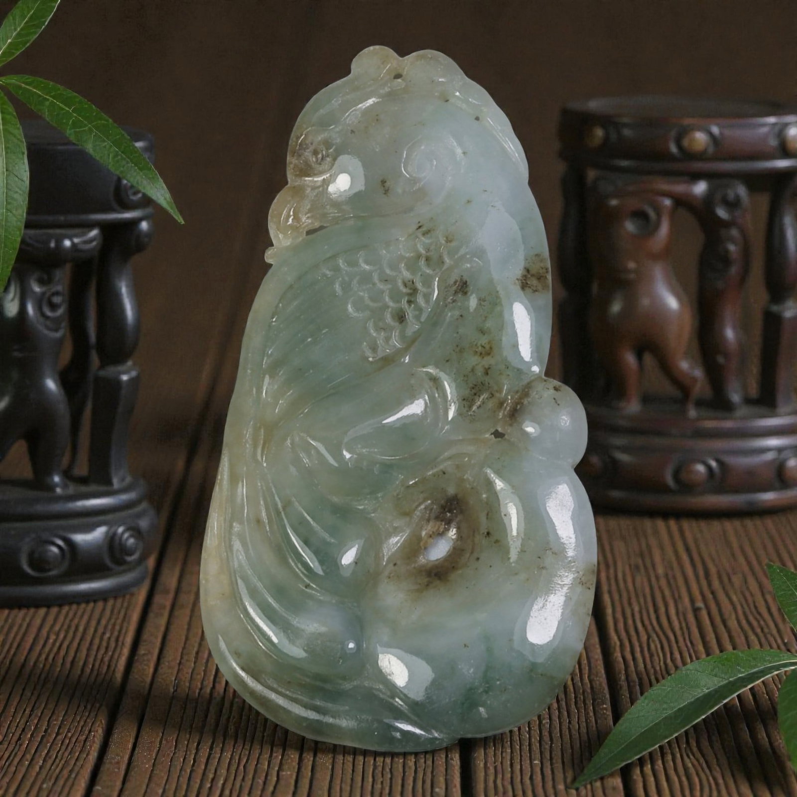 An Antique Oriental Chinese Jadeite Jade Bird Pendant, 40AG: Carved from pale green and white jadeite jade with natural brownish inclusions and subtle tonal variations, the pendant depicts a stylized bird form. The bird is shown in profile with incised feather 