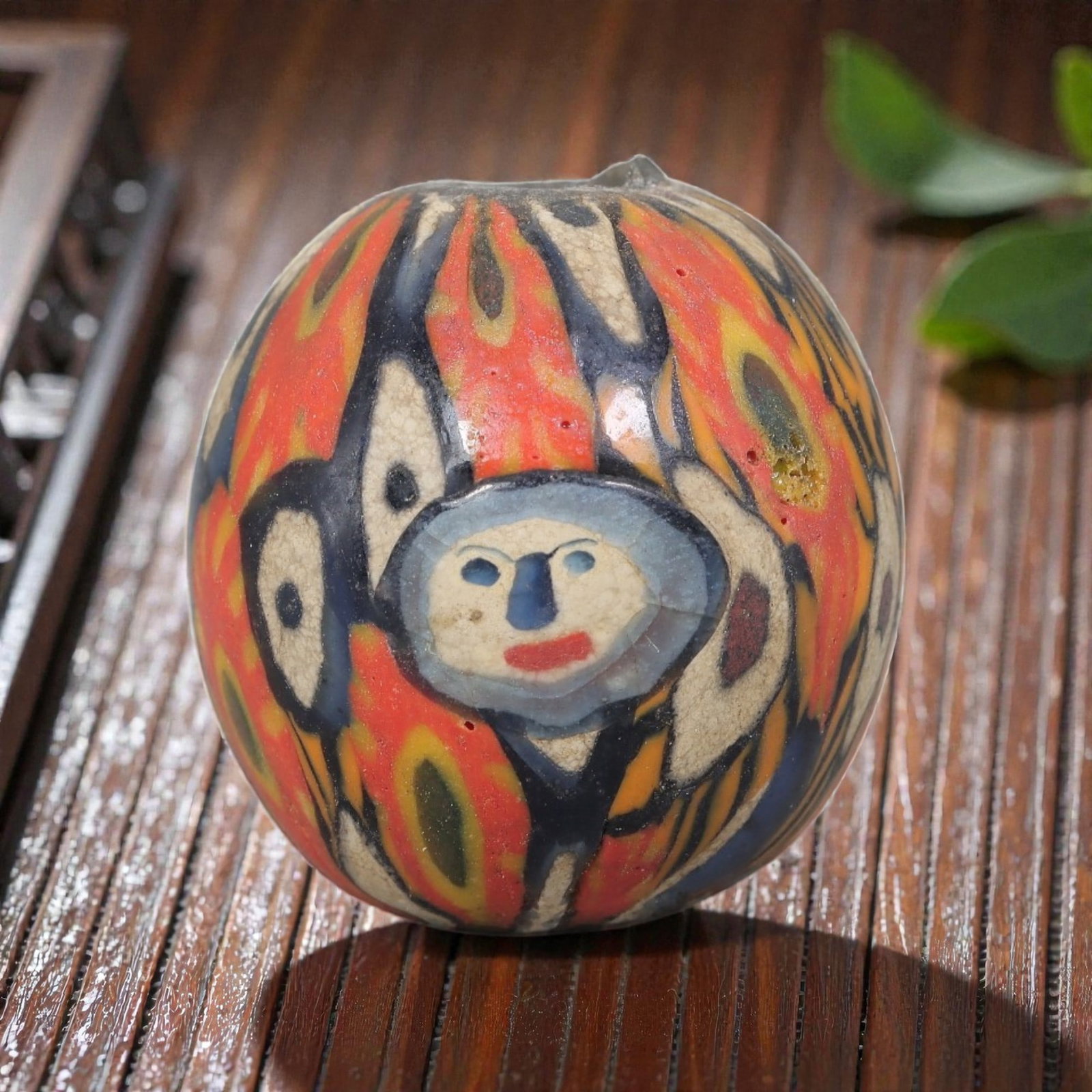 Antique Glass Bead - Islamic Jatim Figural Face Mosaic, 67AP: A spherical glass bead of Islamic Jatim type, crafted from polychrome mosaic glass. The surface features a central stylized figural face motif with defined facial features, surrounded by repeating oce
