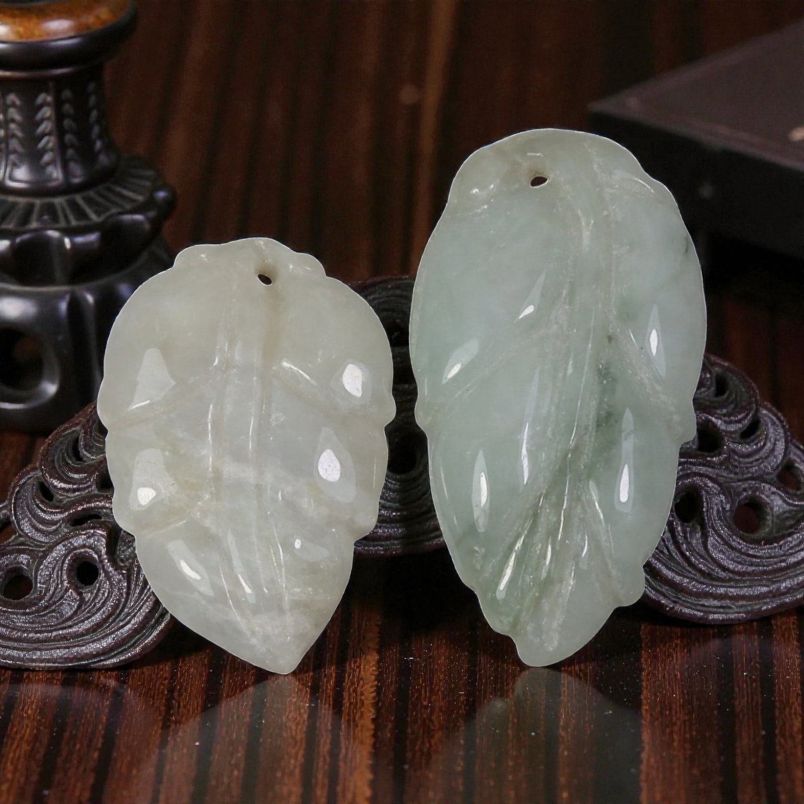 Lot of 2 Antique Oriental Chinese Jadeite Jade Leaf Pendants, 17AG: The lot comprises two leaf-shaped jadeite pendants, each carved from pale-toned stone with natural variations in colour and translucency. The left pendant is predominantly milky white jadeite with sub