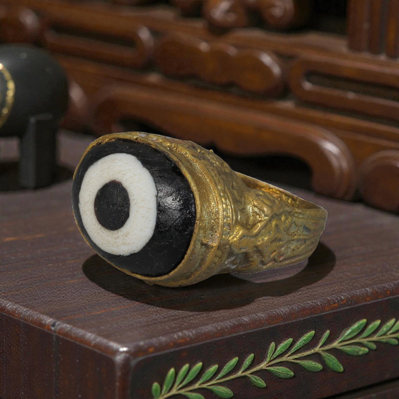 Antique Qajar Dynasty Gilt Evil Eye Ring, US Size 7.5, 36AJ: A gilt-metal ring of the Qajar period, US ring size 7.5, featuring a large domed evil-eye glass inlay with a bold concentric black-and-white design (the glass exhibits age-related cracks and patina). 