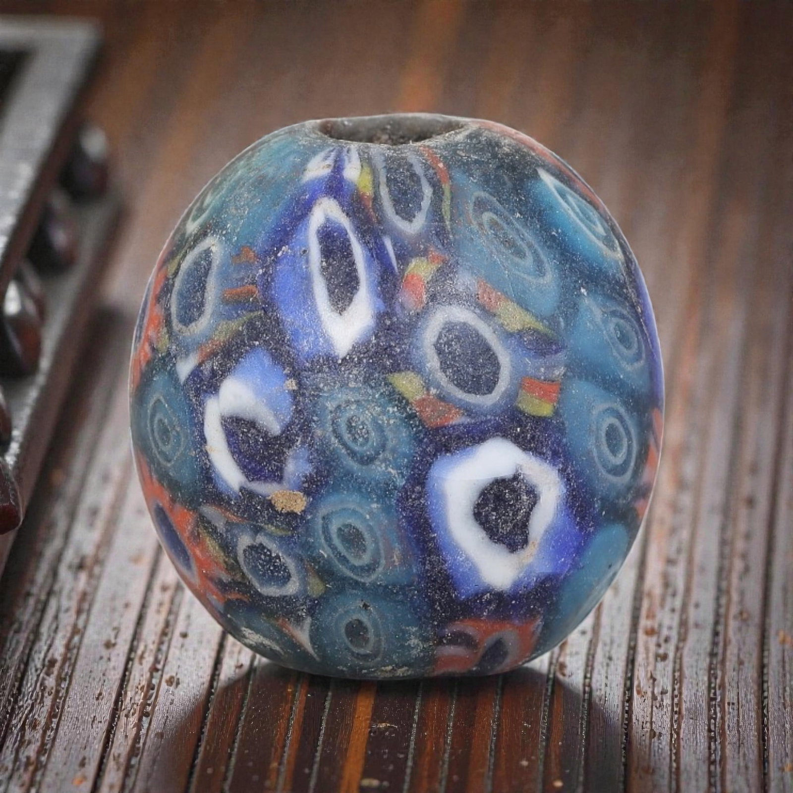 Antique Glass Bead - Islamic Jatim Multicolor Eye Mosaic, 43YH: A spherical glass bead of Islamic Jatim type, crafted from polychrome mosaic glass. The surface features dense repeating eye motifs with dark centers framed by white rings, set against a richly layere