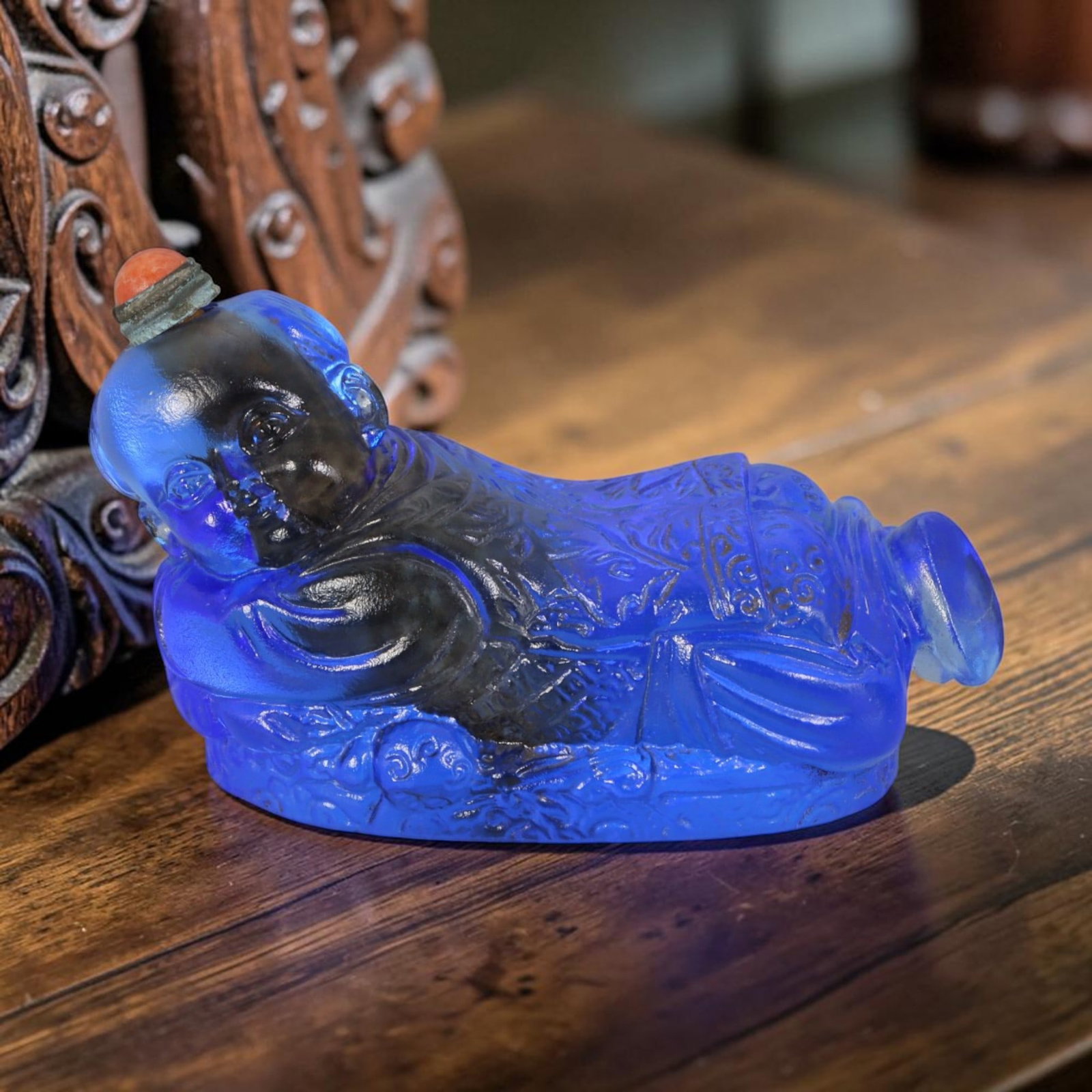 Vintage Chinese Liuli Glass Snuff Bottle - Reclining Lucky Child Embossed Sapphire Blue Vessel, 46AS: This sculpted anthropomorphic snuff bottle is handcrafted from translucent frosted sapphire blue vintage Chinese liuli glass, molded as a reclining traditional lucky child figure resting on an elabora