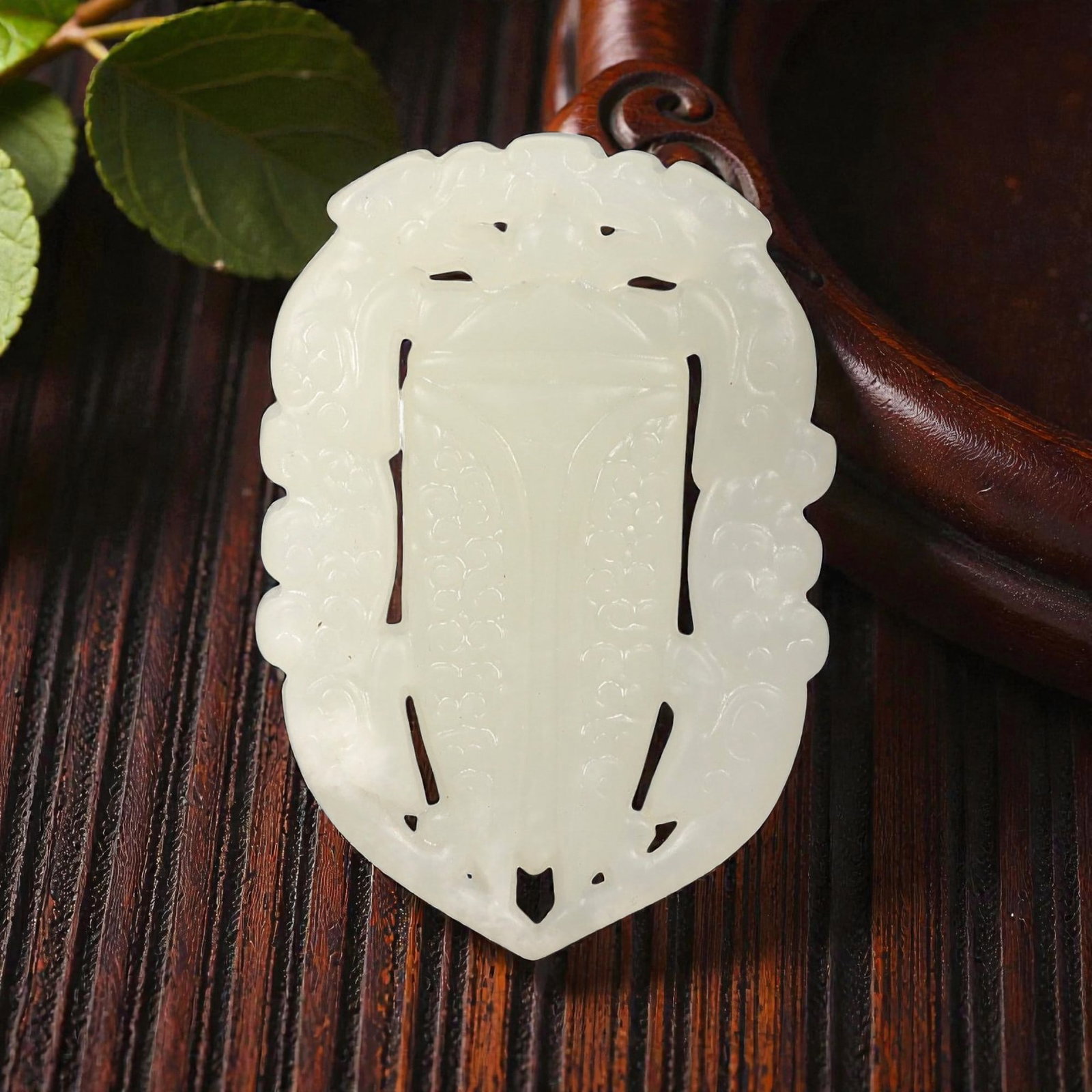 A Chinese Archaistic-Style Jade Openwork Plaque Pendant, 43FH: Carved from pale translucent jade with a milky white tone and subtle internal clouding, the plaque is formed as a vertically oriented openwork panel with a symmetrical outline tapering to a pointed lo