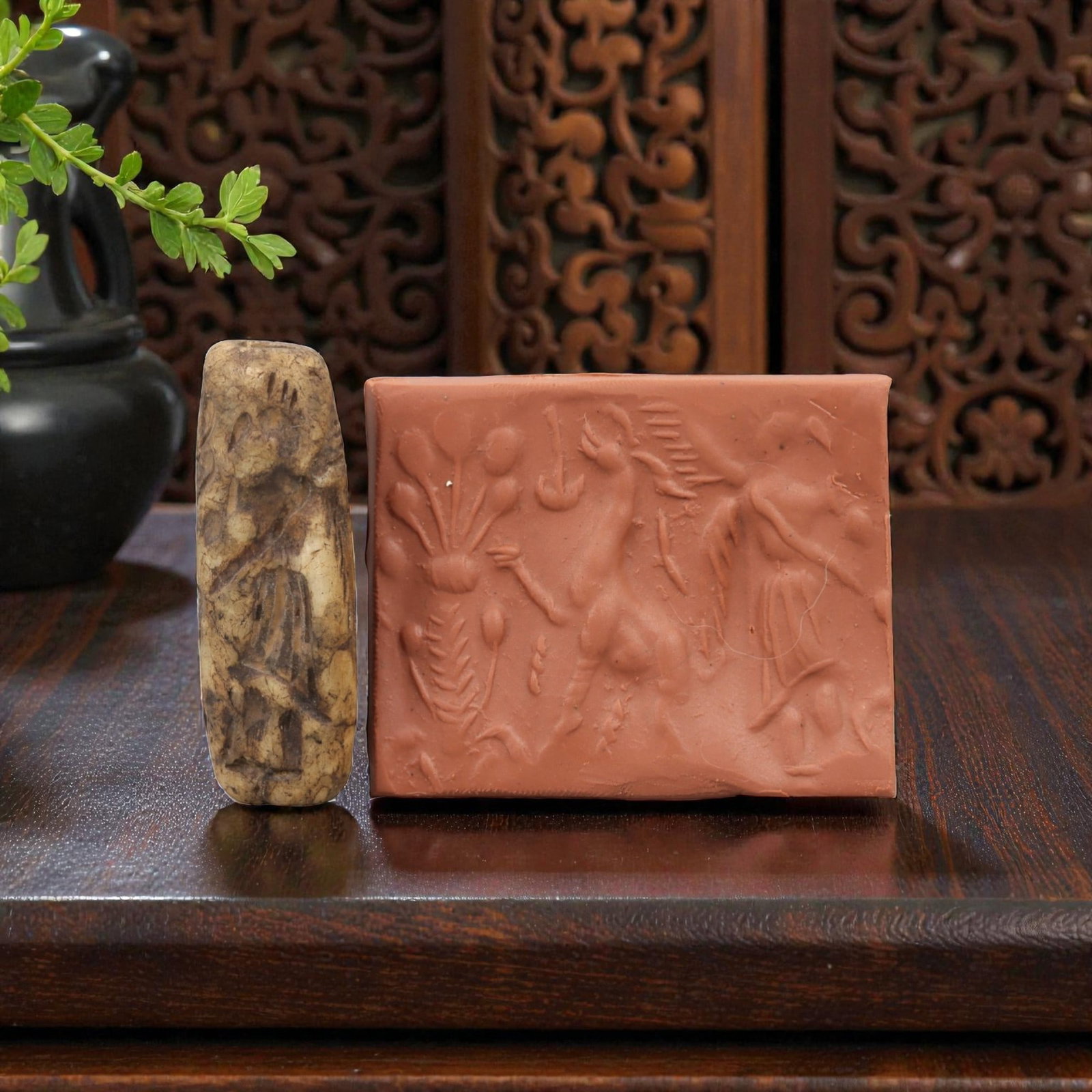 Ancient Steatite Cylinder Seal - Mesopotamian Mythological & Botanical Scene, 77AN: Carved from dense steatite, this ancient Mesopotamian cylinder seal features a detailed linear relief composition of a winged humanoid figure, caprine creature, and botanical motifs, executed in the c
