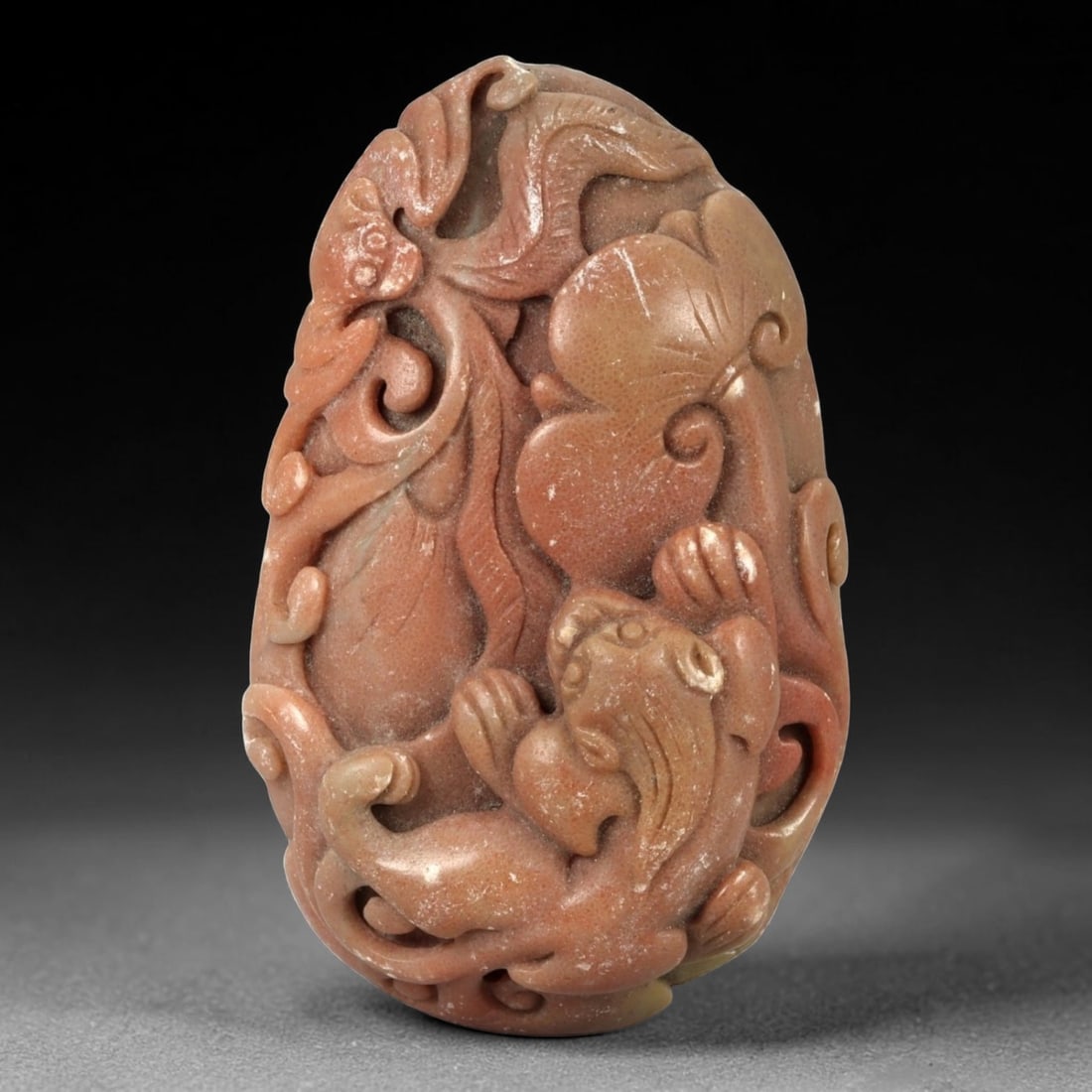 A Chinese Hardstone Carving with a Mythical Beast Pendant, 96FC: Carved from reddish-brown hardstone with subtle tonal variation and a matte to softly polished surface, the object is worked as a vertical plaque with rounded edges. The composition is executed in hig