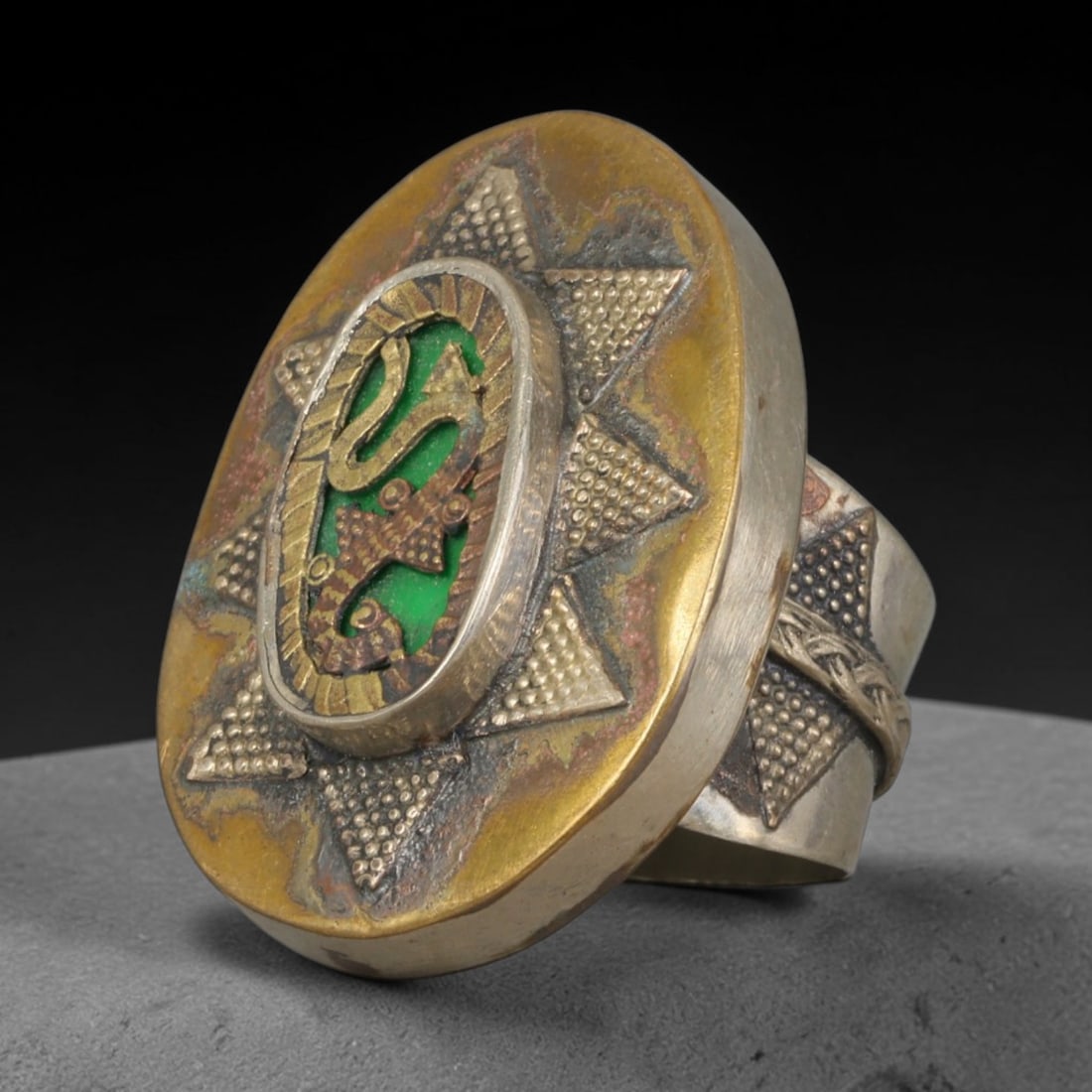 Antique Central Asian Mixed Metal Green Enamel Serpent Star Statement Ring, 67AA: Vintage antique nomadic tribal ring constructed from dual-tone silvered and brass mixed metal, featuring a large oval ring face measuring 3.6cm x 2.8cm. The layered design features an eight-pointed gr