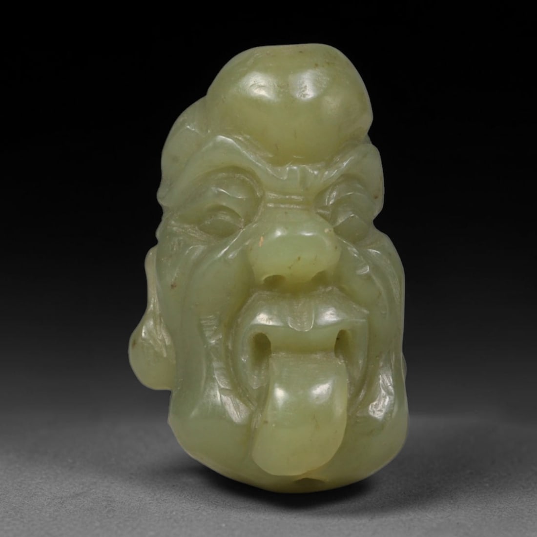 Natural Vintage Chinese Nephrite Jade Pale Celadon Playful Arhat Head Carved Face Bead, 99AA: Hand-carved vintage Chinese strung bead crafted from natural vintage Chinese nephrite jade, measuring 3cm x 1.8cm. This barrel-form bead is uniquely sculpted into a whimsical Buddhist Arhat facial bus