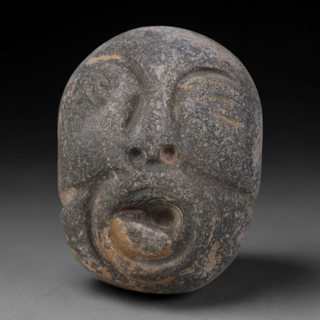 Ancient Medieval Mediterranean Hand Carved Stone Maskette Amulet, 52AP: Miniature wearable sacred talisman hand hewn from natural soft stone, originating from Medieval Mediterranean cultural craft traditions. Small carved stone amulets were widespread personal artifacts a