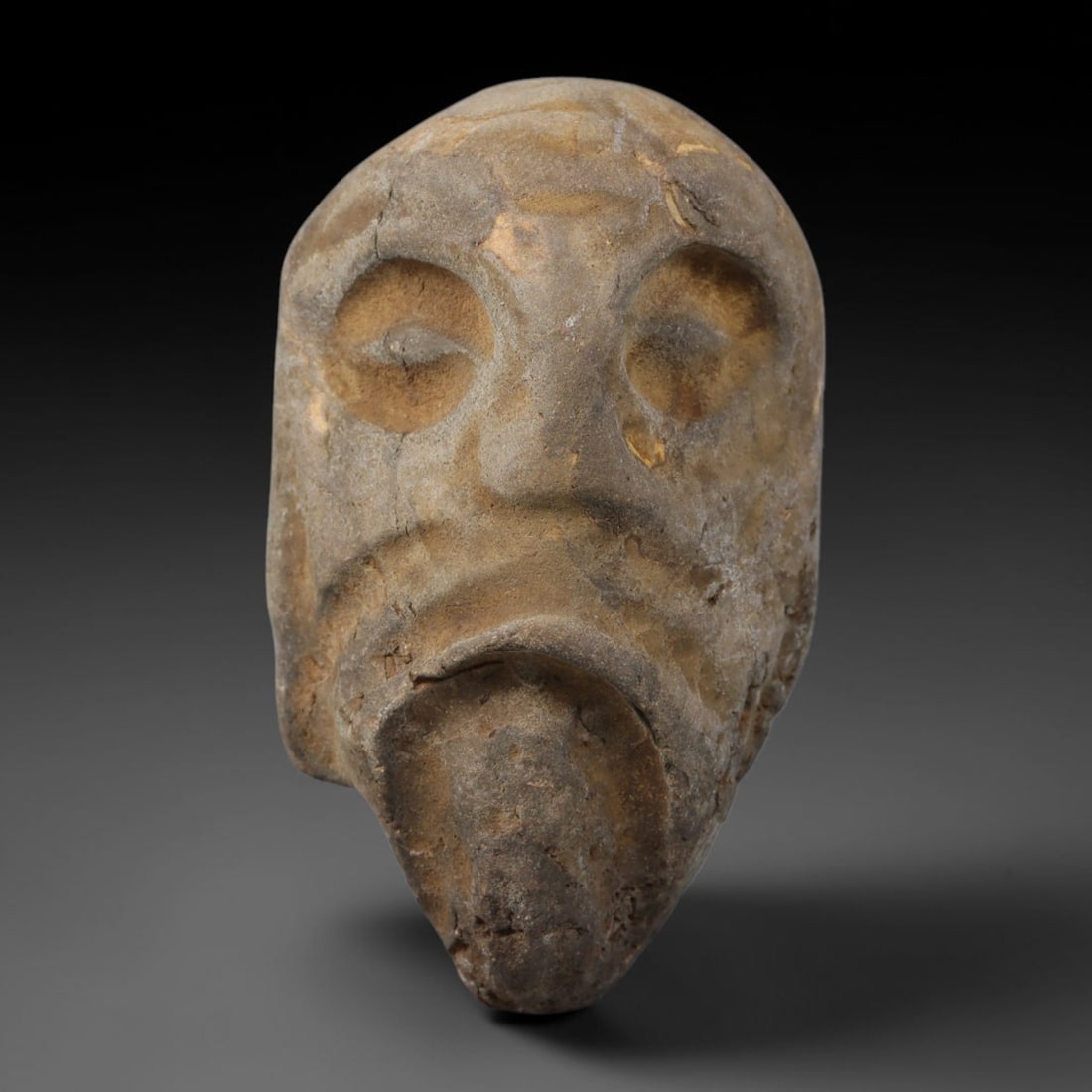 Ancient Medieval Near Eastern Tribal Hand Carved Stone Maskette Amulet, 44AC: Medium-sized antique wearable talisman hand hewn from natural sedimentary stone, measuring 5cm x 3cm, originating from Medieval Near Eastern tribal cultural traditions. Hand-carved stone talismans hel