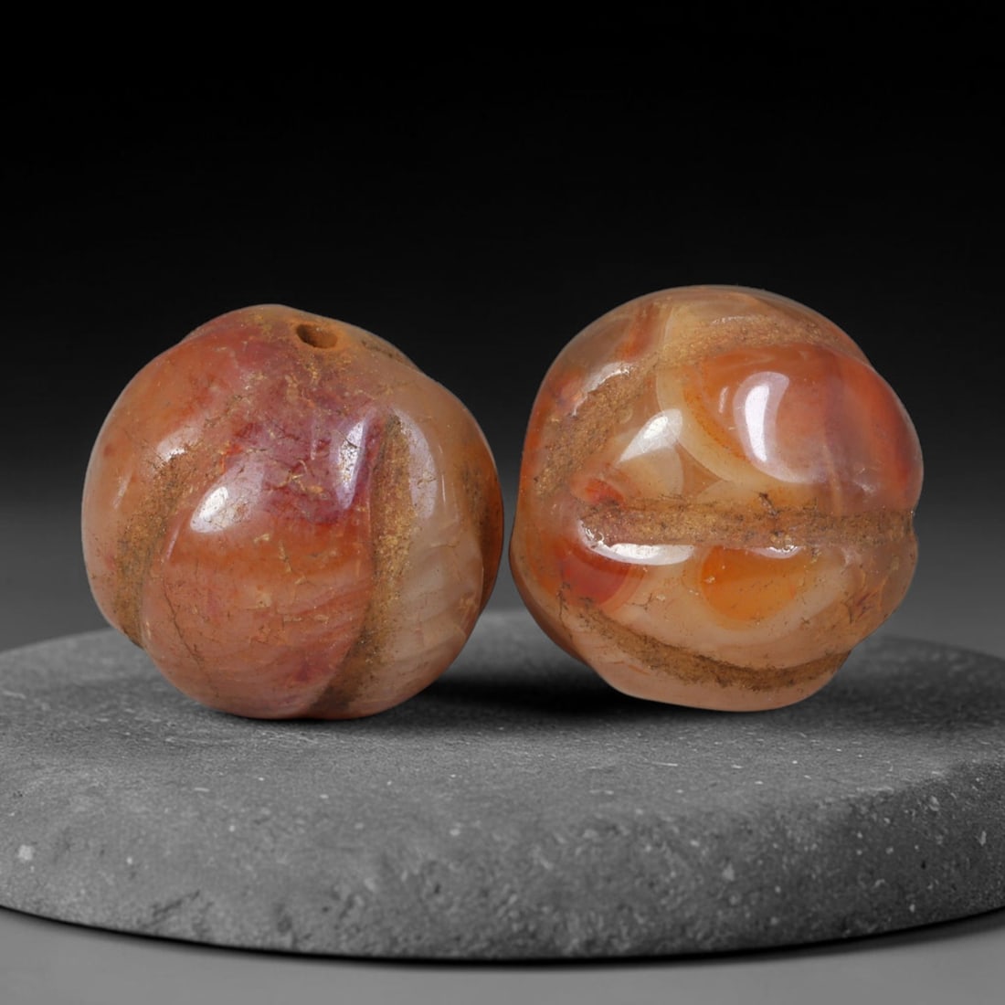 Ancient Medieval Khmer Angkor Culture Carved Carnelian Melon Bead Pair (802-1431 CE), 40AE: This matched pair of antique hand-carved melon form carnelian beads originates from Khmer Angkor Culture, the medieval Southeast Asian civilization renowned for crafting ritual chalcedony adornments f
