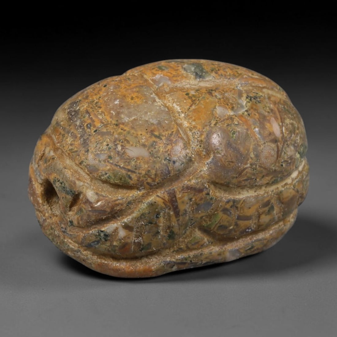 Ancient Egyptian Late Period Natural Patterned Jasper Scarab Amulet (664-30 BCE), 56AB: Hand-carved domed scarab pendant crafted from multicoloured brecciated jasper with natural warm ochre, green and grey mineral patterning throughout the stone matrix. Deep incised lines delineate the b