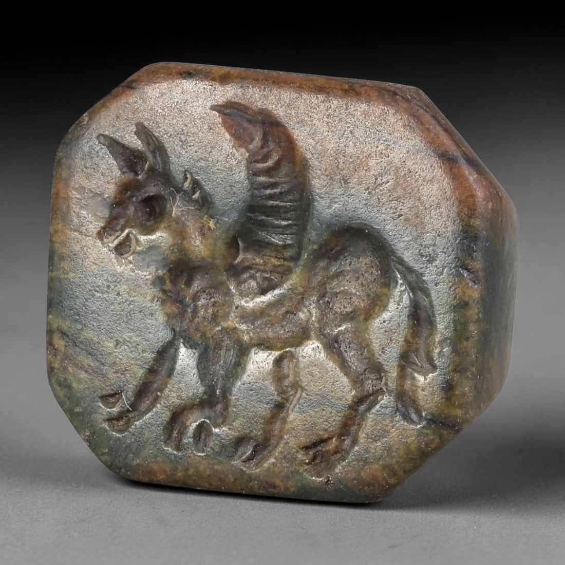 Ancient Sasanian Persian Banded Stone Winged Creature Stamp Seal (224-651 CE), 73AB: This marbled brown-green stone pyramid stamp originates from Sasanian Persian Culture, elite personal seal amulets carved with mythic winged beast motifs for marking documents and talismans. A large s