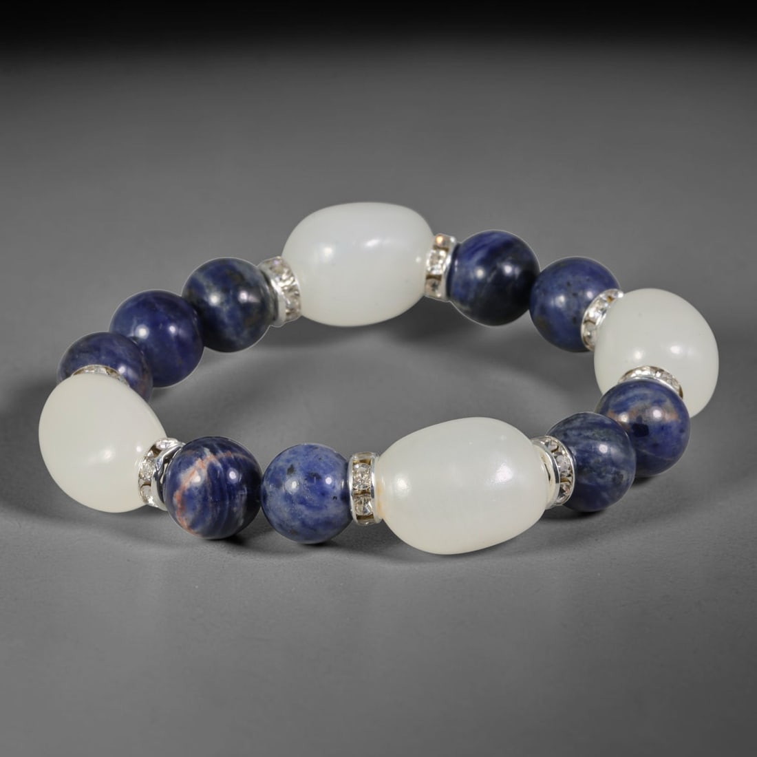 Natural Sodalite & White Jade Beaded Bracelet - Mixed Shape Bead Strand, 48FA: This elastic stretch bracelet alternates 10mm spherical polished sodalite beads with barrel-shaped polished white jade beads, separated by silvered metal spacers set with clear crystalline accents. Th