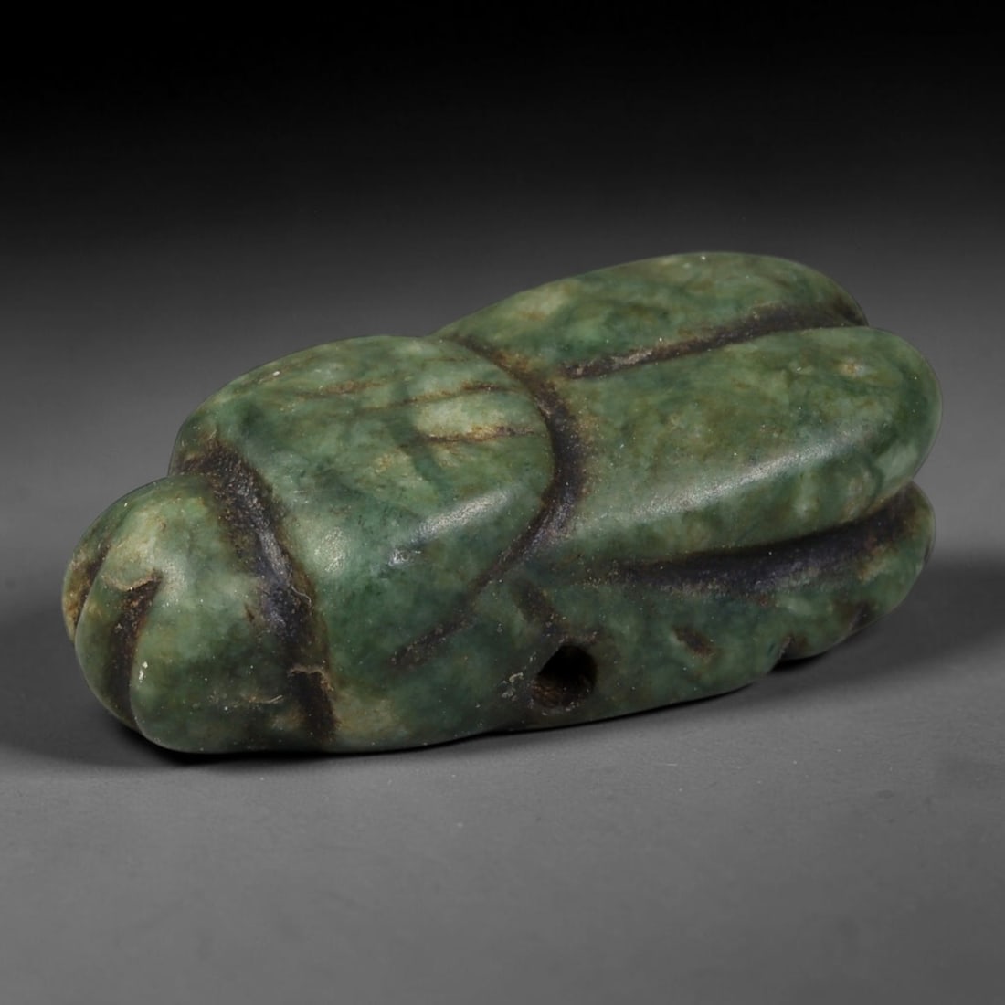 Ancient Egyptian Green Serpentine Scarab Amulet (664-30 BCE), 62AB: Carved from mottled deep green serpentine, this compact scarab talisman bears soft ancient polish across rounded beetle contours. Deep dark mineral patina lines the carved segmentation grooves, a smal