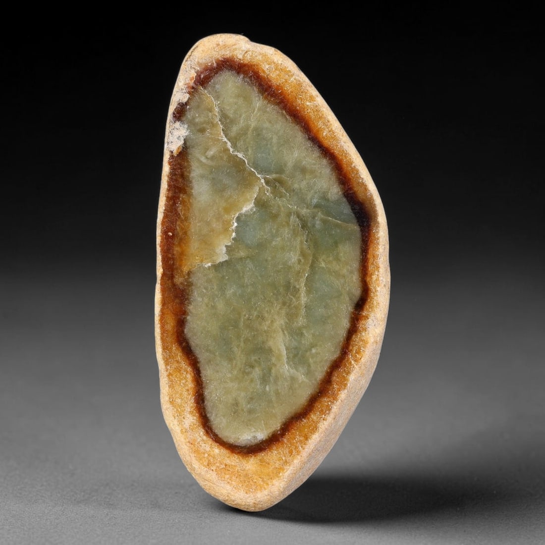390ct Natural Type A Burmese Double Layer Red Skin Rim Olive Green Jadeite Jade Sliced Rough, 17FA: This specimen is a teardrop-shaped sliced rough pebble of untreated Type A Burmese jadeite, featuring a distinctive two-tiered skin formation: an outer pale yellow weathered cortex surrounding a defin