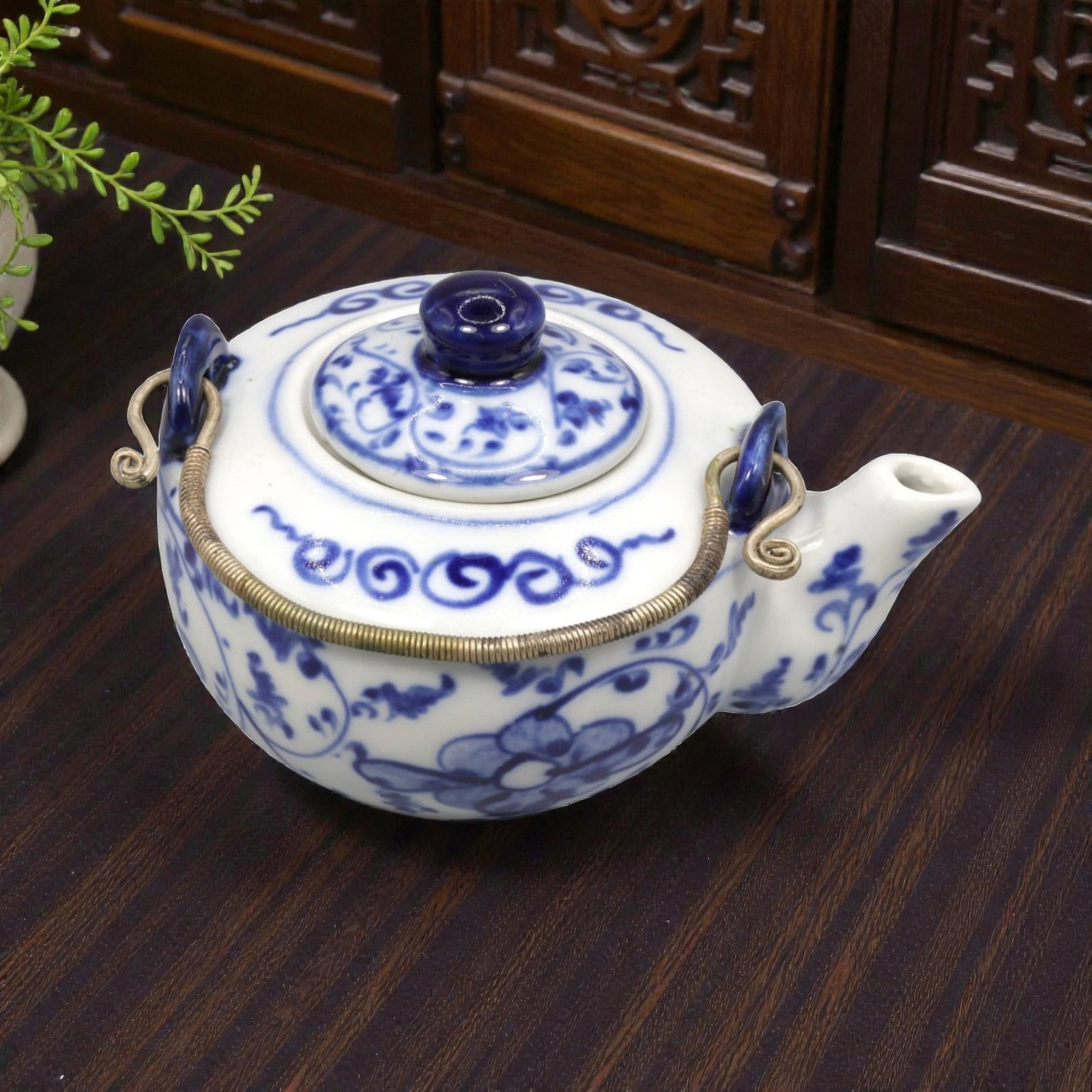 A Chinese Blue and White Porcelain Teapot, 20th Century, 52FK: The teapot is formed with a compressed globular body resting on a short foot, fitted with a domed cover surmounted by a circular knop, and equipped with a short projecting spout and a metal swing hand