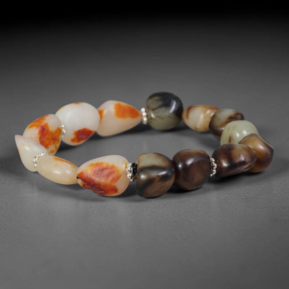 Natural Chinese Xinjiang Hetian Nephrite Jade Pebble Bracelet, 74AE: This bracelet features polished natural Xinjiang Hetian nephrite river pebble beads with organic freeform contours, accented by small silver-toned spacer beads between each stone. The jade displays a 