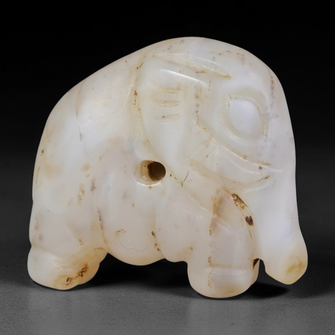 Ancient Western Asiatic Natural White Agate Elephant Zoomorphic Amulet (1000-600 BCE), 30AB: Hand-carved pale milky agate pendant crafted into a stylized standing elephant, a sacred symbol of wisdom, prosperity and protective power in ancient Western Asiatic cultures. Subtle linear incisions 