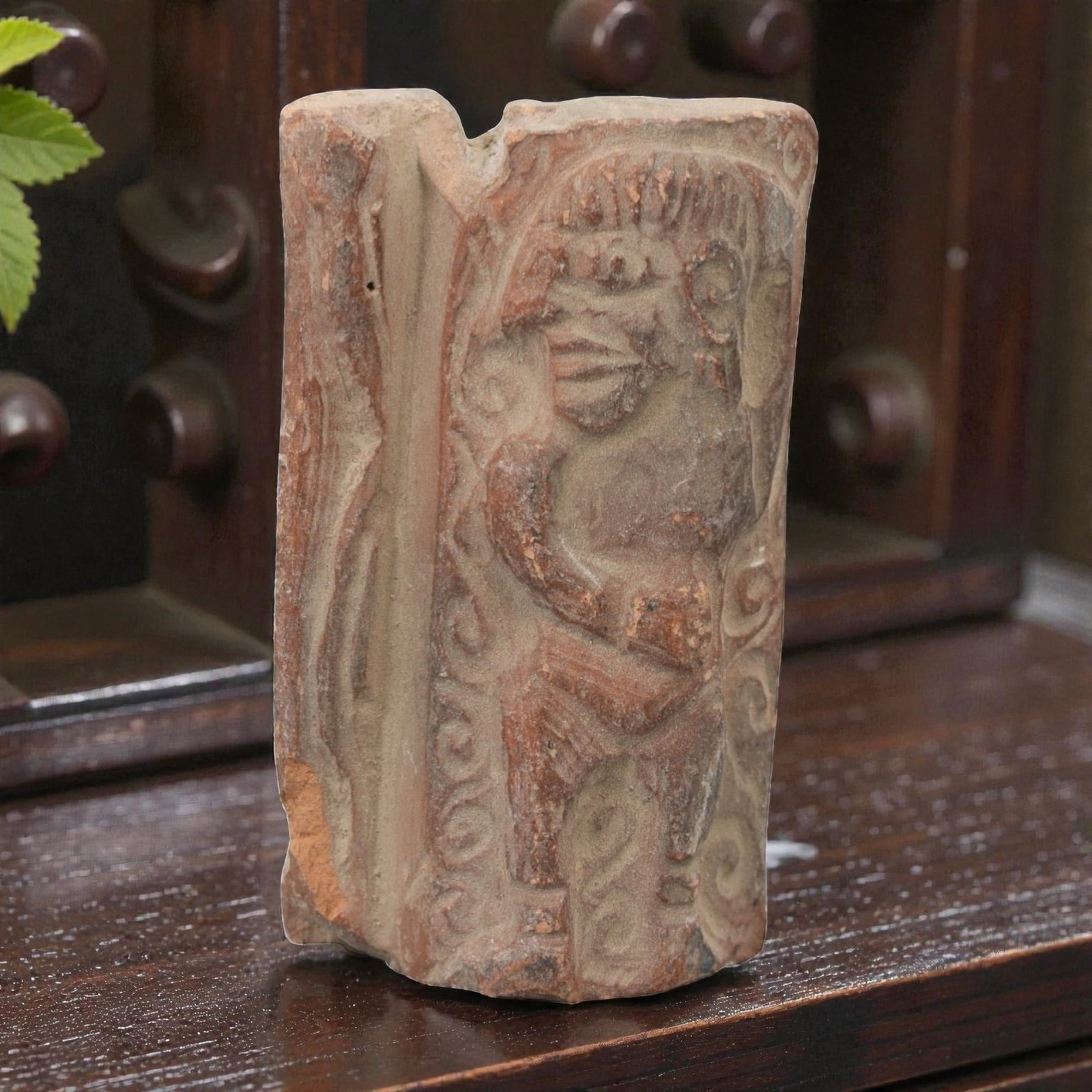 A Near Eastern Terracotta Plaque, 3rd-2nd Millennium BCE, 81FL: Molded from reddish-brown terracotta with natural surface patination and visible edge losses, the object is formed as a rectangular plaque fragment. The relief depicts a standing humanoid figure with 