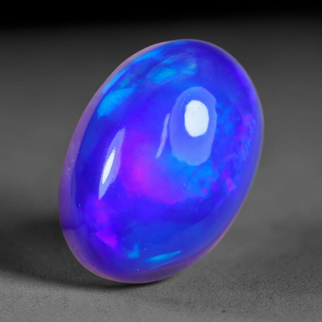 3.94 Carats Natural Ethiopian Welo Violet Blue Opal Cabochon Loose Gemstone, 60AG: This striking opal carries a saturated deep violet and electric blue iridescent glow across its smooth polished dome, measured at 13.4x9.6x6.1mm, the uniform rich cool-toned flash delivers bold eye-ca