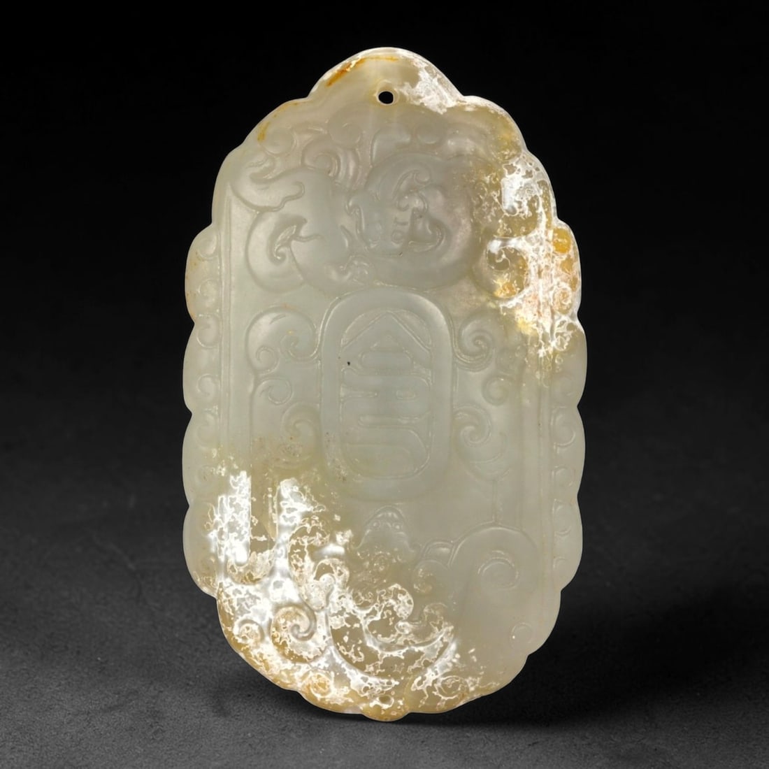 A Chinese Hetian Nephrite Jade Longevity Plaque, Qing Dynasty, 18th-19th Century, 26FA: Carved from pale celadon jade with areas of translucent milky tone and natural russet-brown inclusions, the plaque is of vertically oriented rectangular form with a rounded upper edge. The surface is 