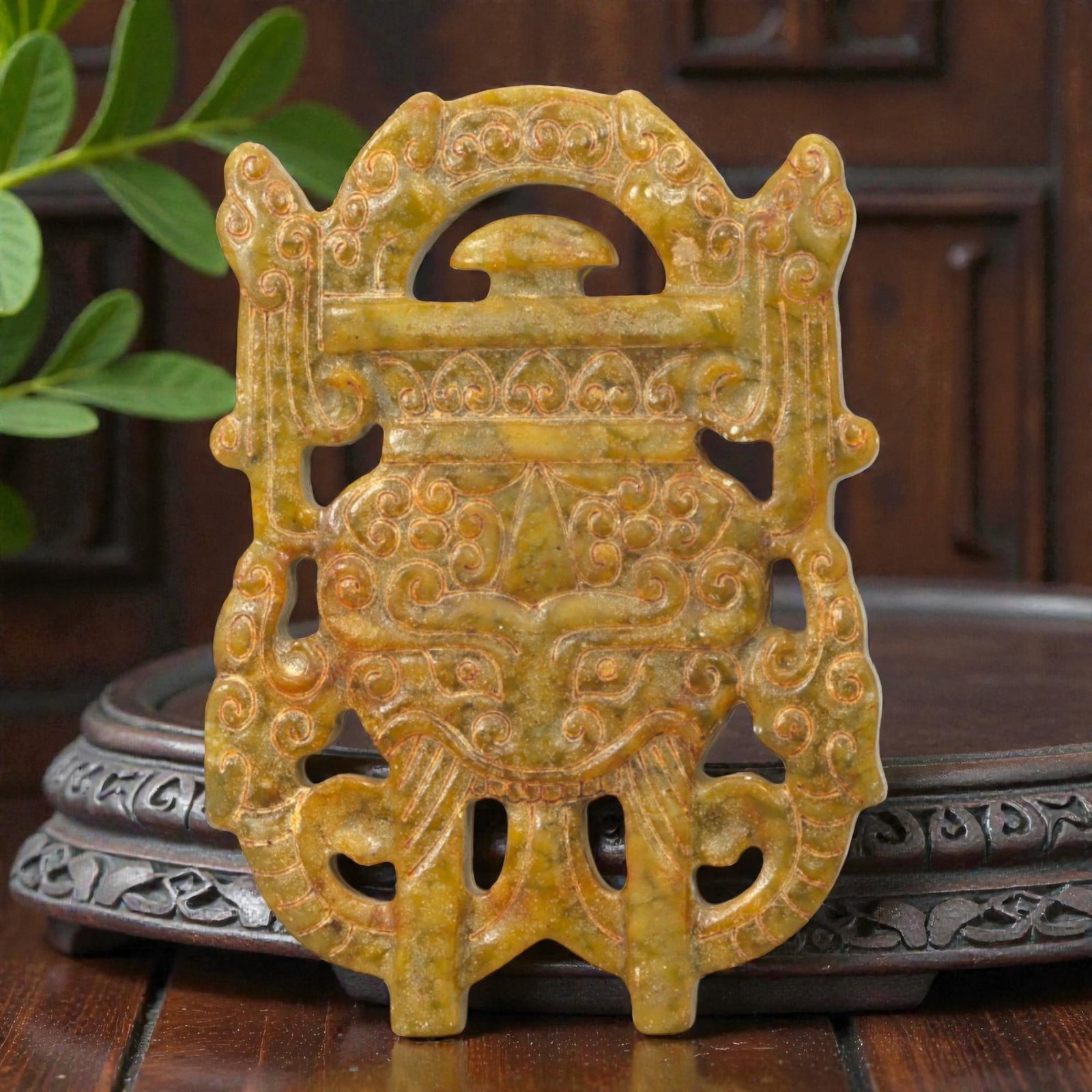 A Chinese Jade Openwork Plaque, 20th Century, 52FC: Carved from mottled jade with olive-green and warm russet tones, the plaque is worked in openwork and low relief to form a symmetrical, vertically oriented composition. The design is dominated by an a