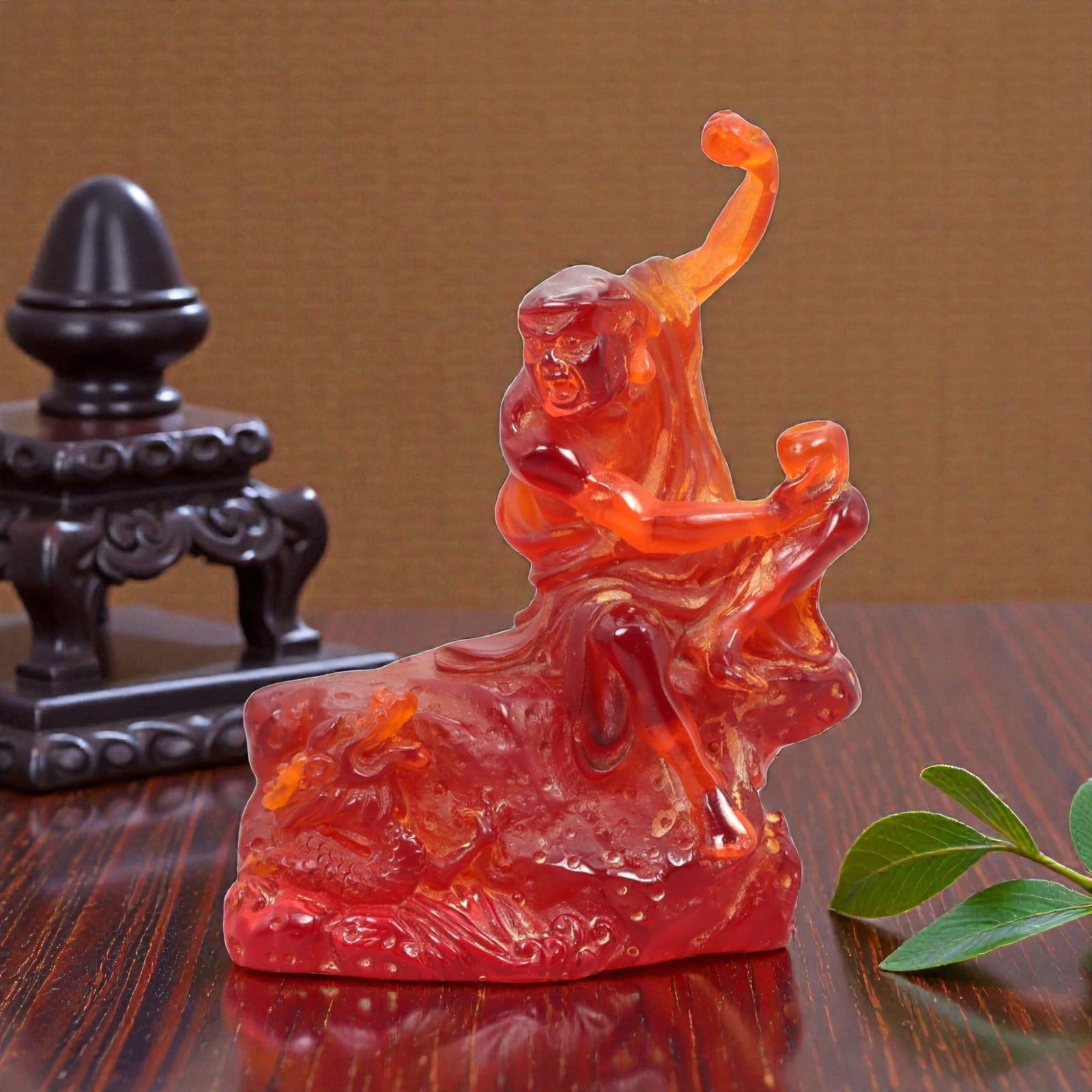 A Chinese Amber-Resin Figure of a Luohan, 20th Century, 34FH: Cast or carved from translucent amber-colored red resin with internal tonal variation, scattered inclusions, and small entrapped bubbles, the figure represents a luohan shown seated in a dynamic postu