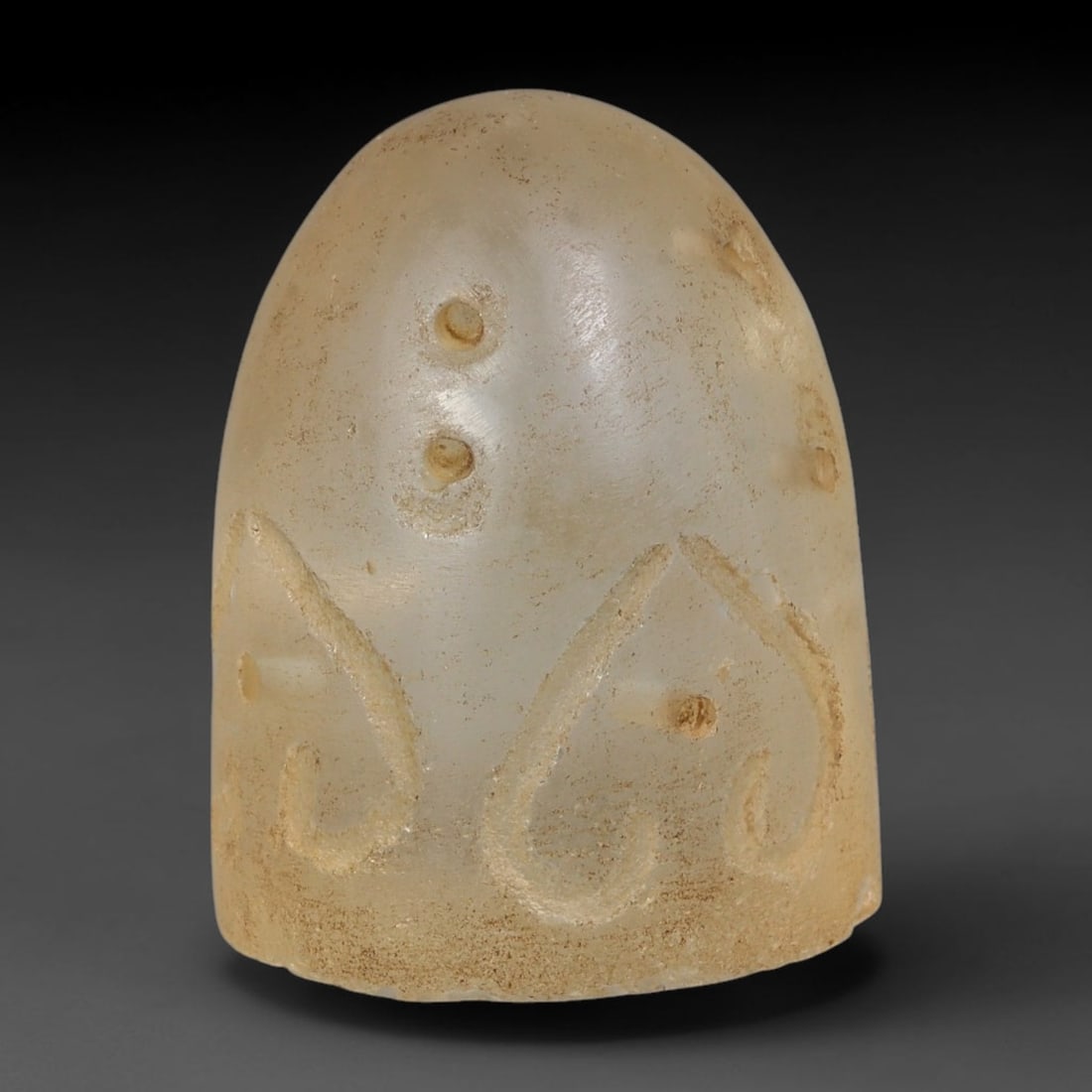 Ancient Medieval Mamluk Islamic Pale Glass Conical Bell Form Talisman (1250-1517 CE), 96AE: Domed conical pale glass talisman with soft frosted translucency, hand-engraved with stylized teardrop scroll motifs paired with small drilled dot accents across the surface. Fine earthy burial sedime