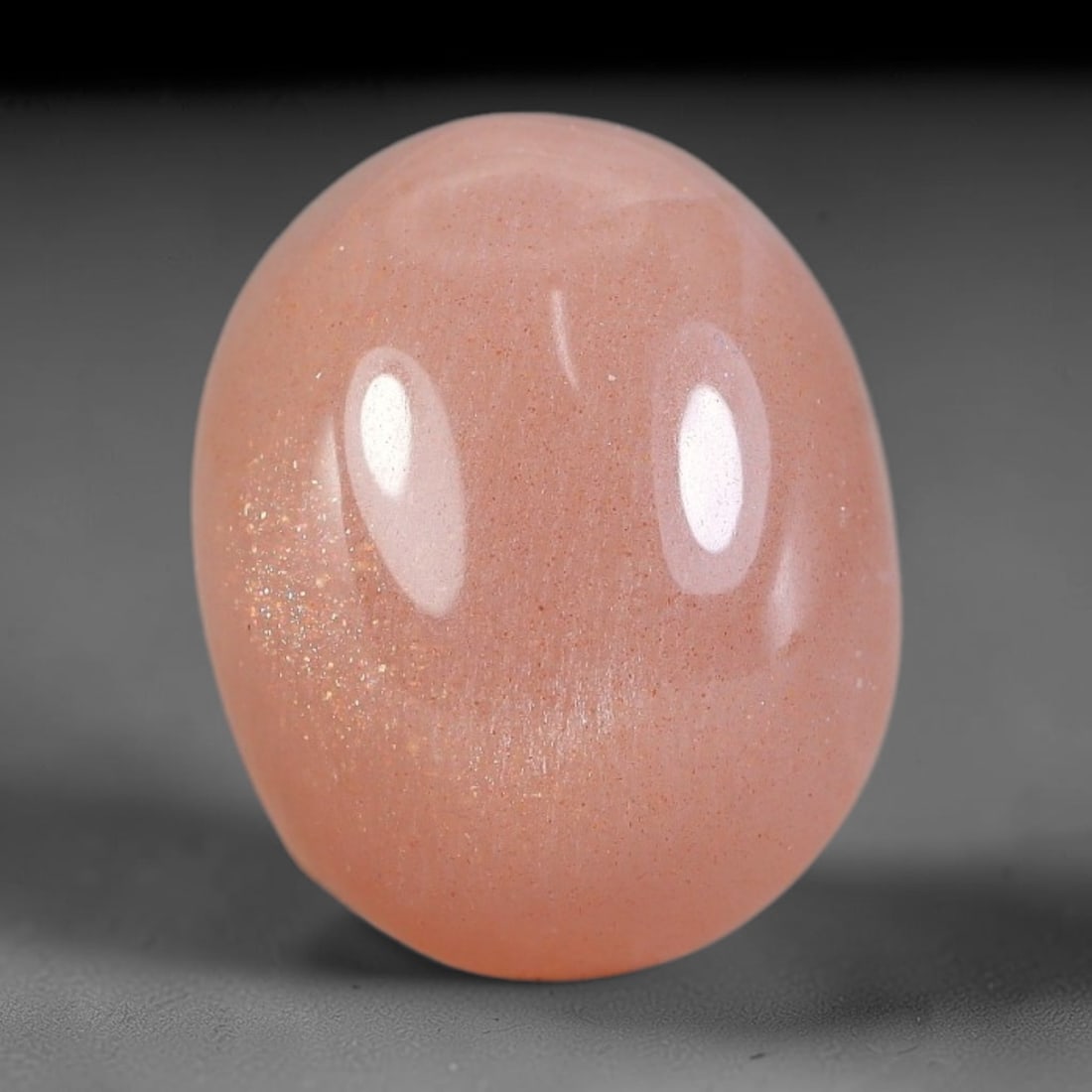 10.10 Carats Natural Ceylon Soft Peach Pink Moonstone Cabochon Loose Gemstone, 3AG: This warm soft peach pink moonstone features delicate sparkling mineral flecks scattered throughout its smooth surface paired with faint flowing adularescent glow, measured at 15x12.1x7.2mm, its gentl