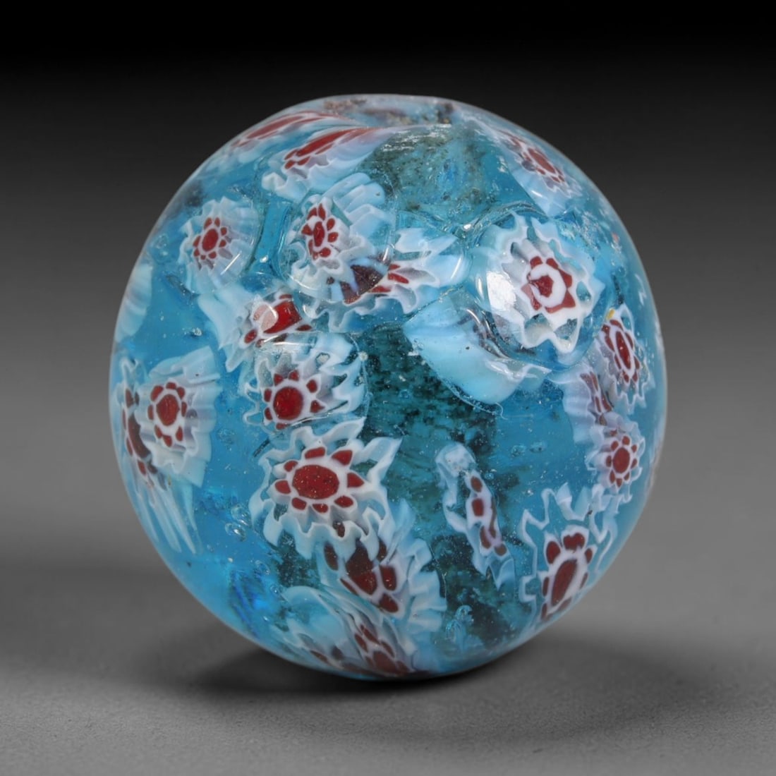 Turquoise Millefiori Blown Glass Bead - Handmade Vintage Spherical Ornament, 23AE: Hand-blown translucent turquoise glass composes this spherical bead, fully adorned with embedded millefiori floral canes featuring layered white petal detailing surrounding deep red central cores dist