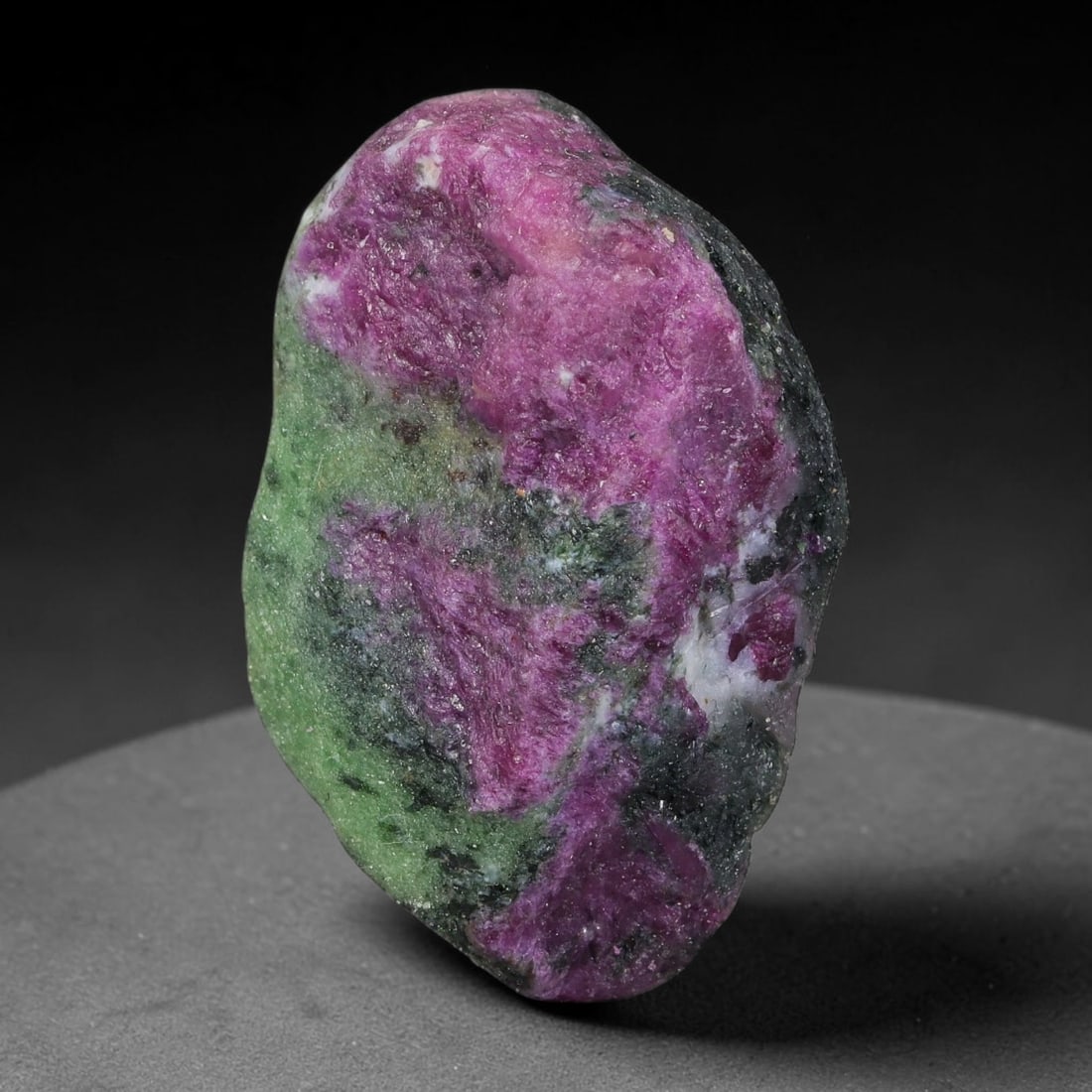 111ct Natural Tanzanian Ruby Zoisite Raw Rough Specimen Mineral Stone, 11FC: This unpolished mineral rough is natural ruby zoisite sourced from Tanzania, exhibiting distinct banded mineral segregation of vibrant green zoisite, magenta ruby crystals, and dark hornblende inclusi