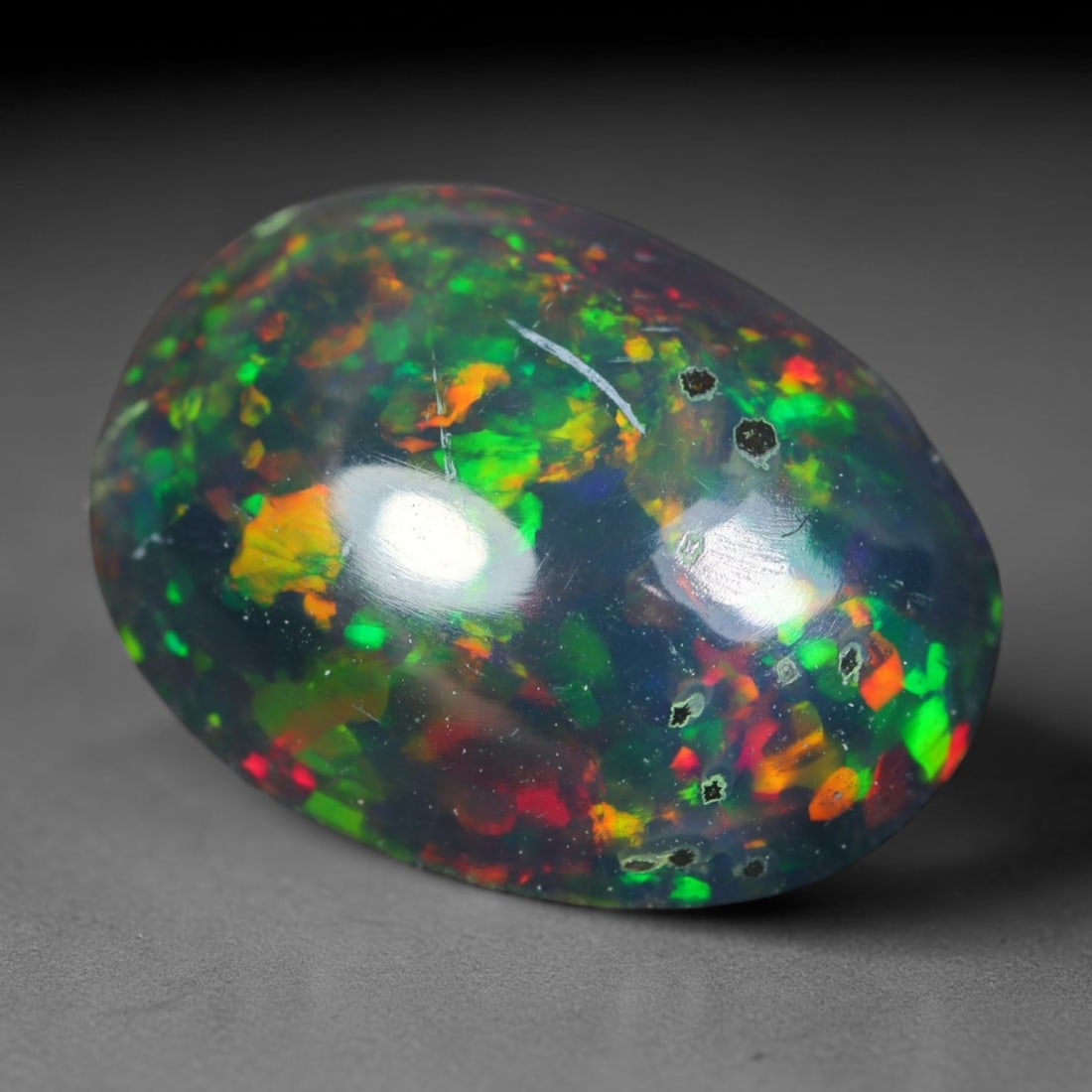 1.51ct Natural Ethiopian Welo Black Smoked Opal Cabochon Loose Gemstone, 88AK: This fully polished Ethiopian Welo opal features a dark smoked base with vivid, sweeping play-of-color shifting across its glossy dome surface, measured at 10.6x8x4.4mm. The black smoke treatment deep