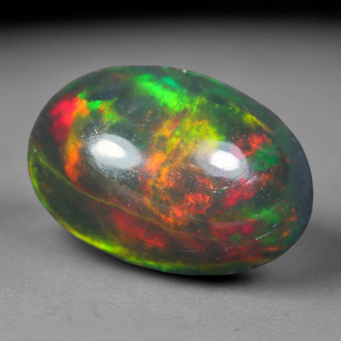 2.15ct Natural Ethiopian Welo Black Smoked Opal Cabochon Loose Gemstone, 85AK: This fully polished Ethiopian Welo opal features a dark smoked base with vivid, sweeping play-of-color shifting across its glossy dome surface, measured at 11.2x7.8x5.1mm. The black smoke treatment de